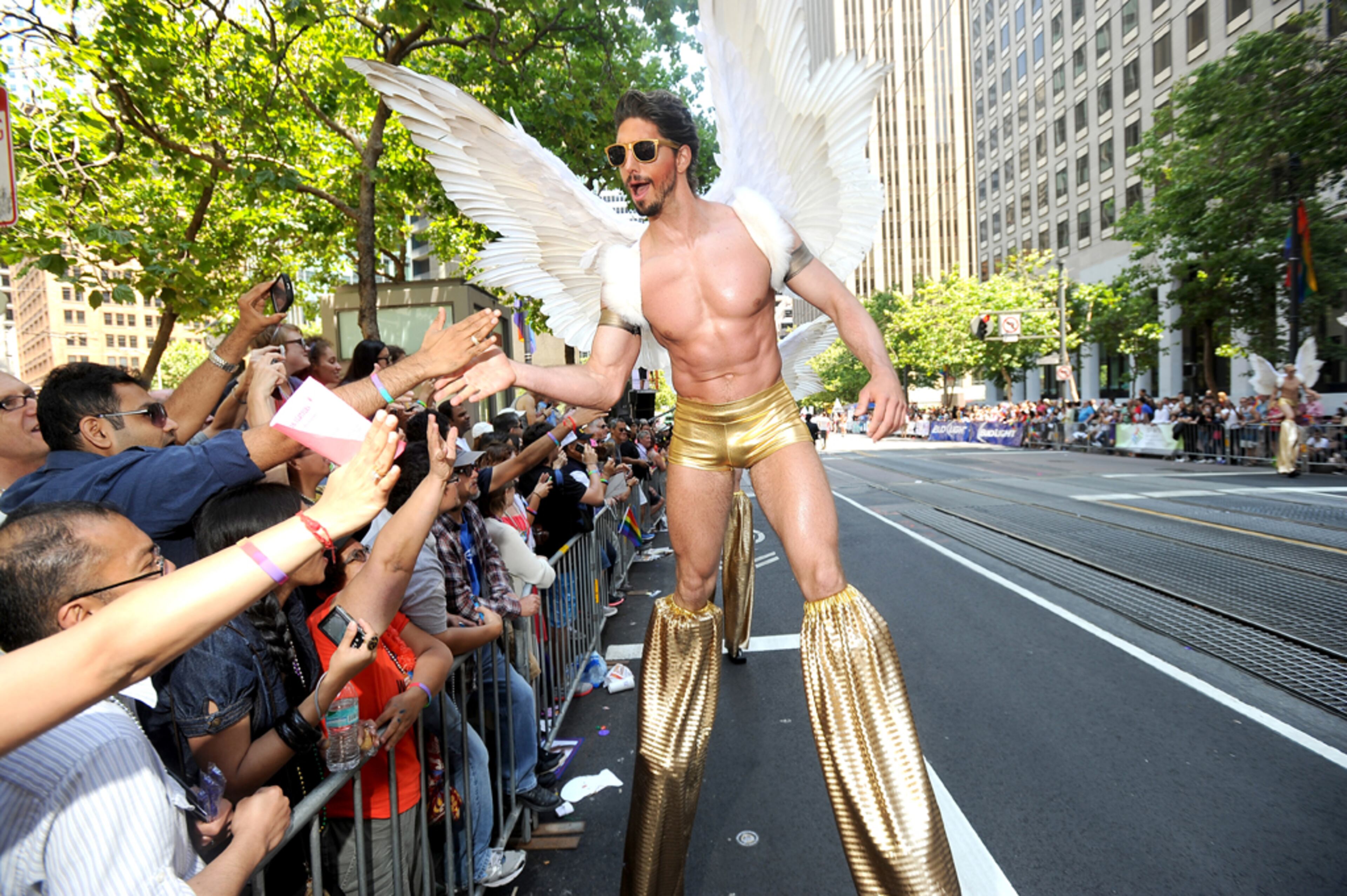 Clad in angel wings and perched on stilts, Joey Reinert shakes hands with spectators during San Francisco's 43rd annual Gay Pride parade on Sunday, June 30, 2013. (AP Photo/Noah Berger)