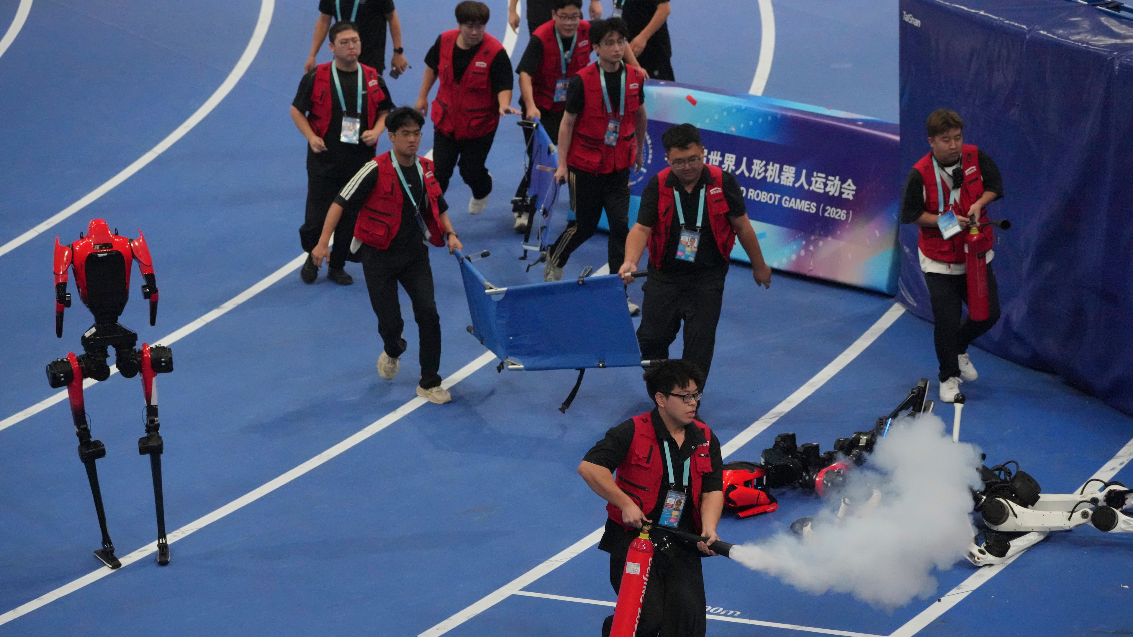 Officials extinguish a fire of a Humanoid robot after hitting the barrier at the end of the 100 meter final race during the World Humanoid Robot Games in Beijing, Wednesday, Aug. 26, 2026. (AP Photo/Achmad Ibrahim)