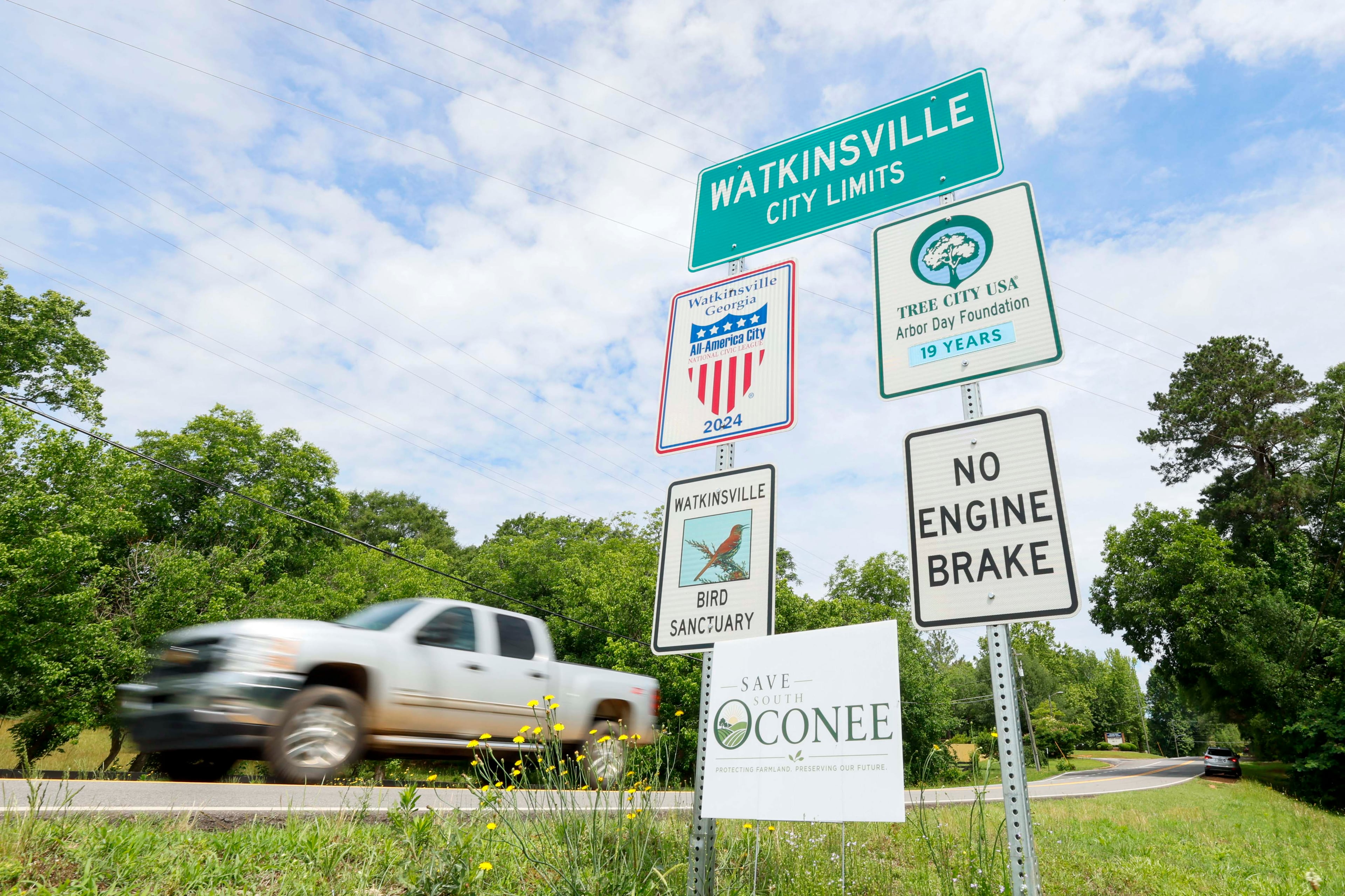 A 'Save South Oconee' sign stands at Watkinsville's city limits on Thursday, May 29, 2026. Opponents of a proposed highway bypass have garnered around 2,500 signatures. (Miguel Martinez/AJC)