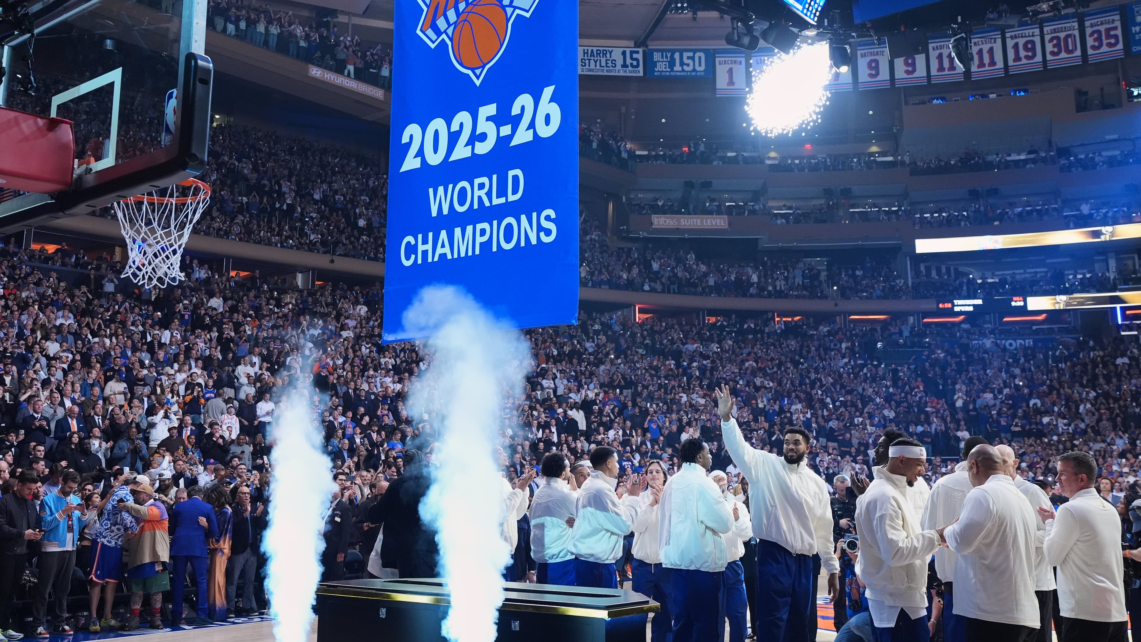 New York Knicks center Karl-Anthony Towns waves as the Knicks 2025-26 World Champions banner is raised before an NBA basketball game between the New York Knicks and the Philadelphia 76ers Tuesday, Oct. 20, 2026, in New York. (AP Photo/Frank Franklin II)