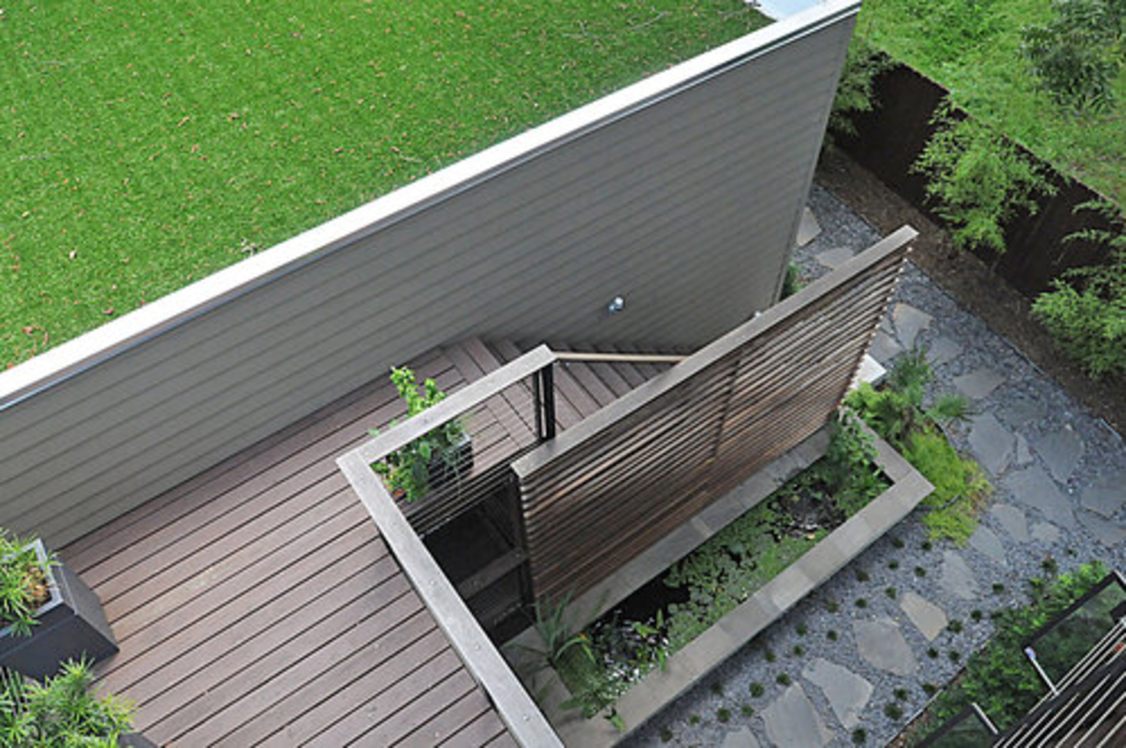 Overhead view of the home's outdoor area as seen from the upper deck. The emerald-green lawn is accessed via a carefully-constructed stone pathway.