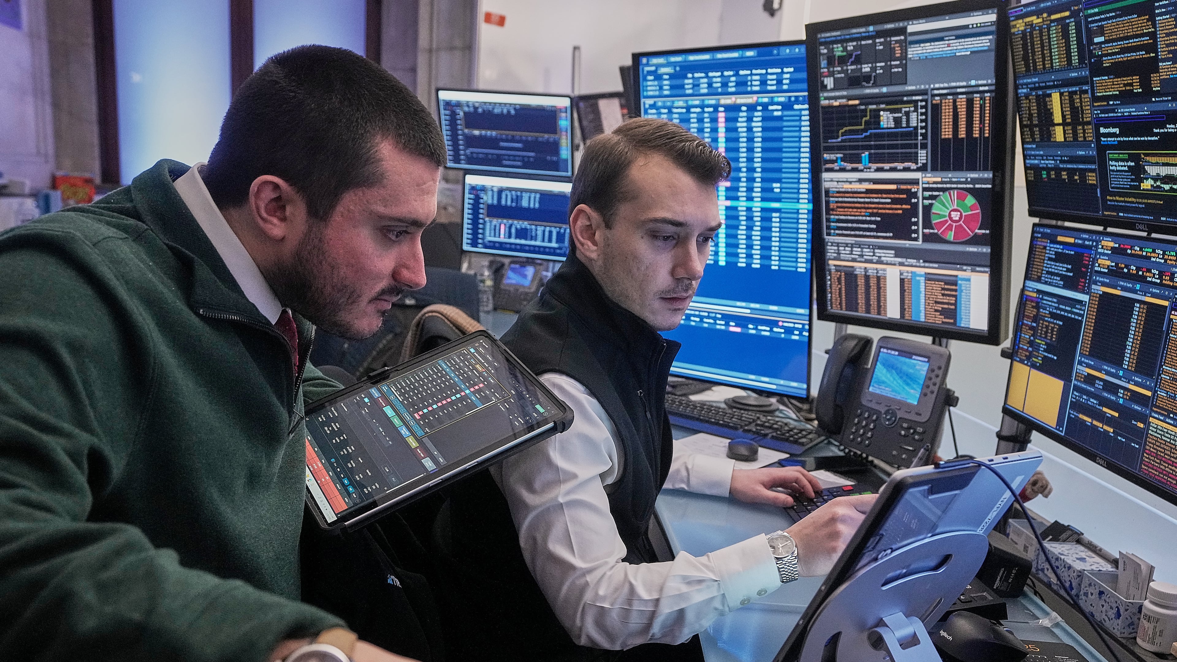 Traders Drew Cohen, left, and Dylan Halvorsan work on the floor of the New York Stock Exchange, Monday, Jan. 26, 2026. (AP Photo/Richard Drew)