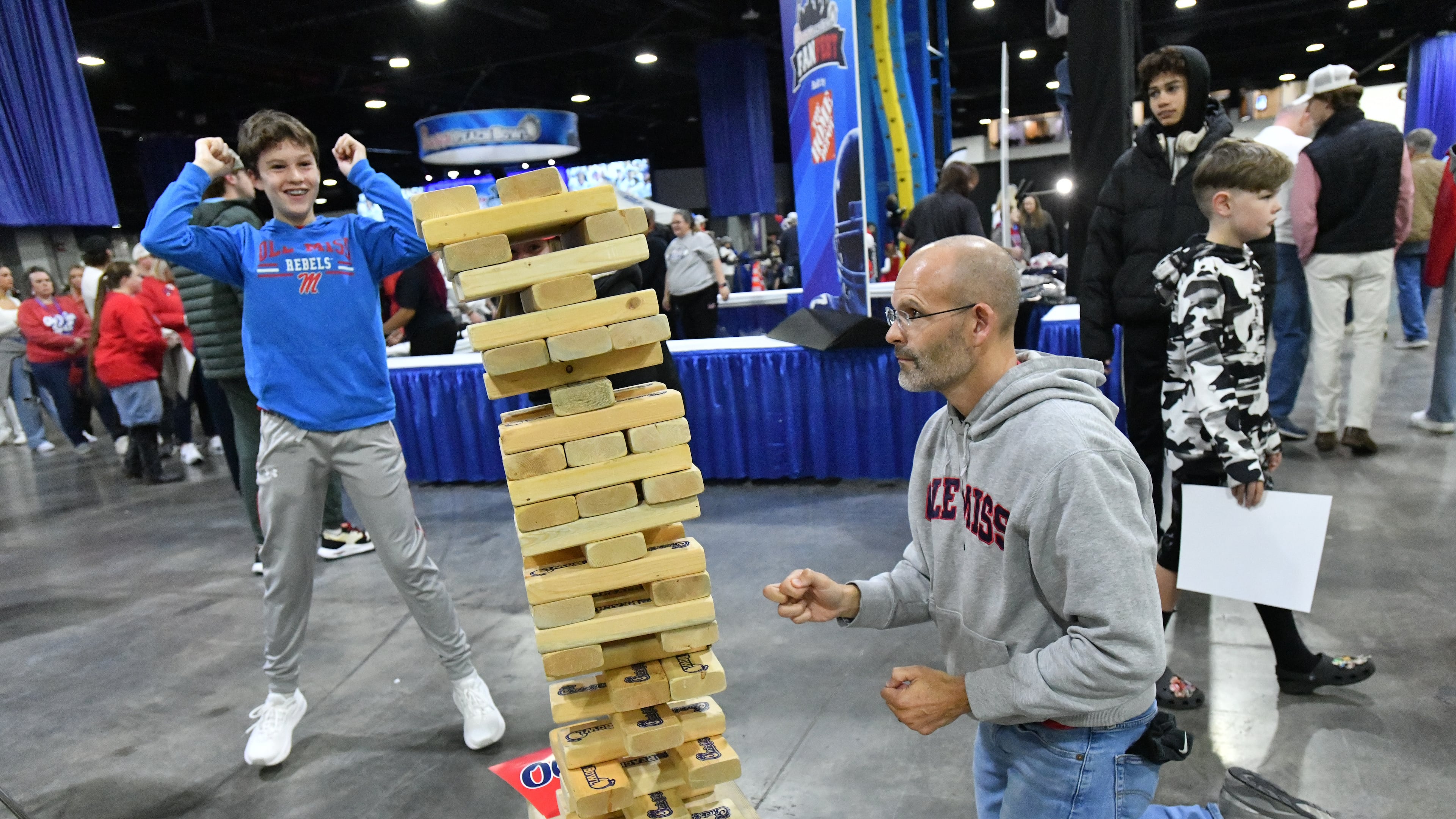 Ole Miss fan Doug Foster plays Jenga as his son Autry (left), 13, reacts during FanFest at Georgia World Congress Center prior to 2023 Chick-fil-A Peach Bowl between Ole Miss and Penn State, Saturday, December 30, 2023, in Atlanta. (Hyosub Shin / Hyosub.Shin@ajc.com)
