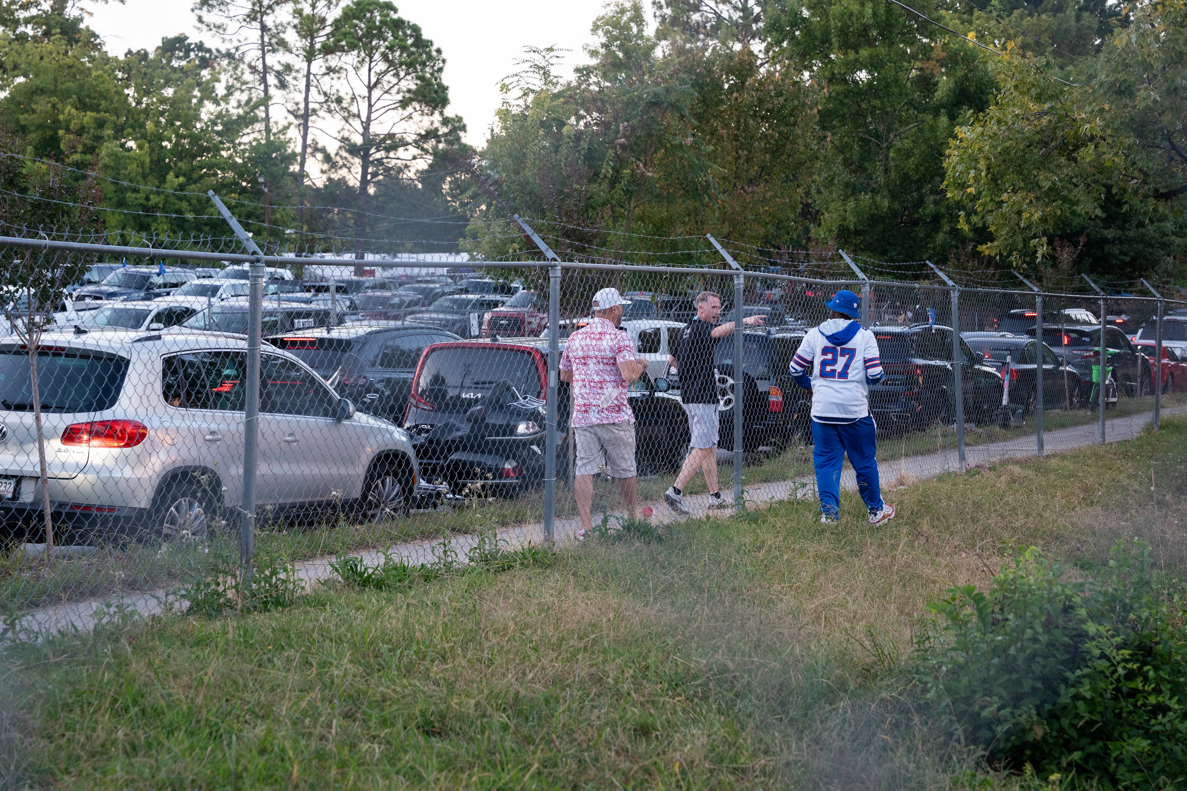 Two Falcons fans banter with a Bills fan across a fence while tailgating before Monday night’s game outside Mercedes-Benz Stadium on Oct. 13, 2025, in Atlanta. (Olivia Bowdoin for the AJC)