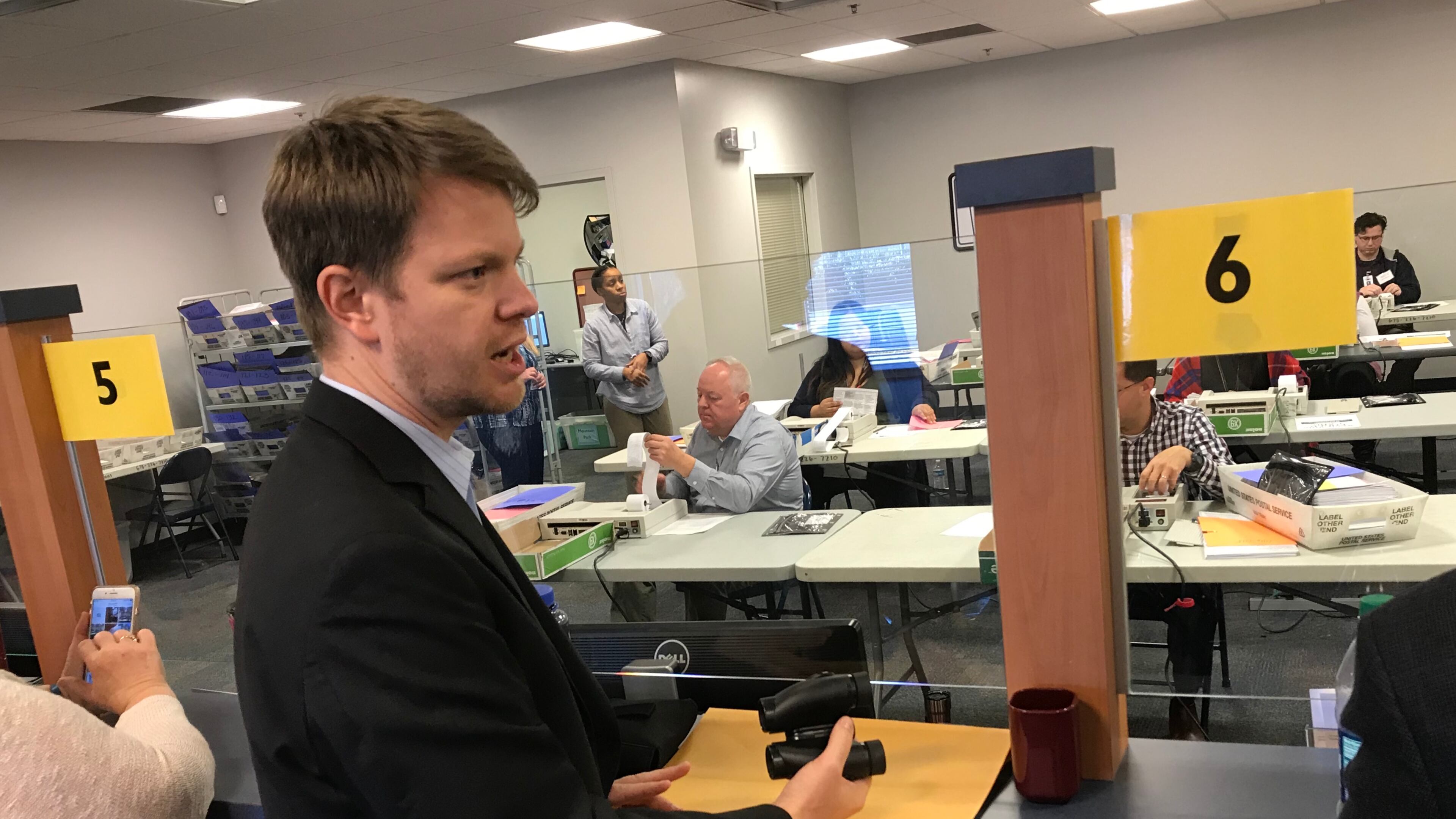 Spencer Smith, the campaign manager for Democratic candidate Carolyn Bourdeaux, holds binoculars Wednesday as the recount for the 7th Congressional District begins. Bourdeaux trails Republican incumbent Rob Woodall by just over 400 votes. TYLER ESTEP / TYLER.ESTEP@AJC.COM