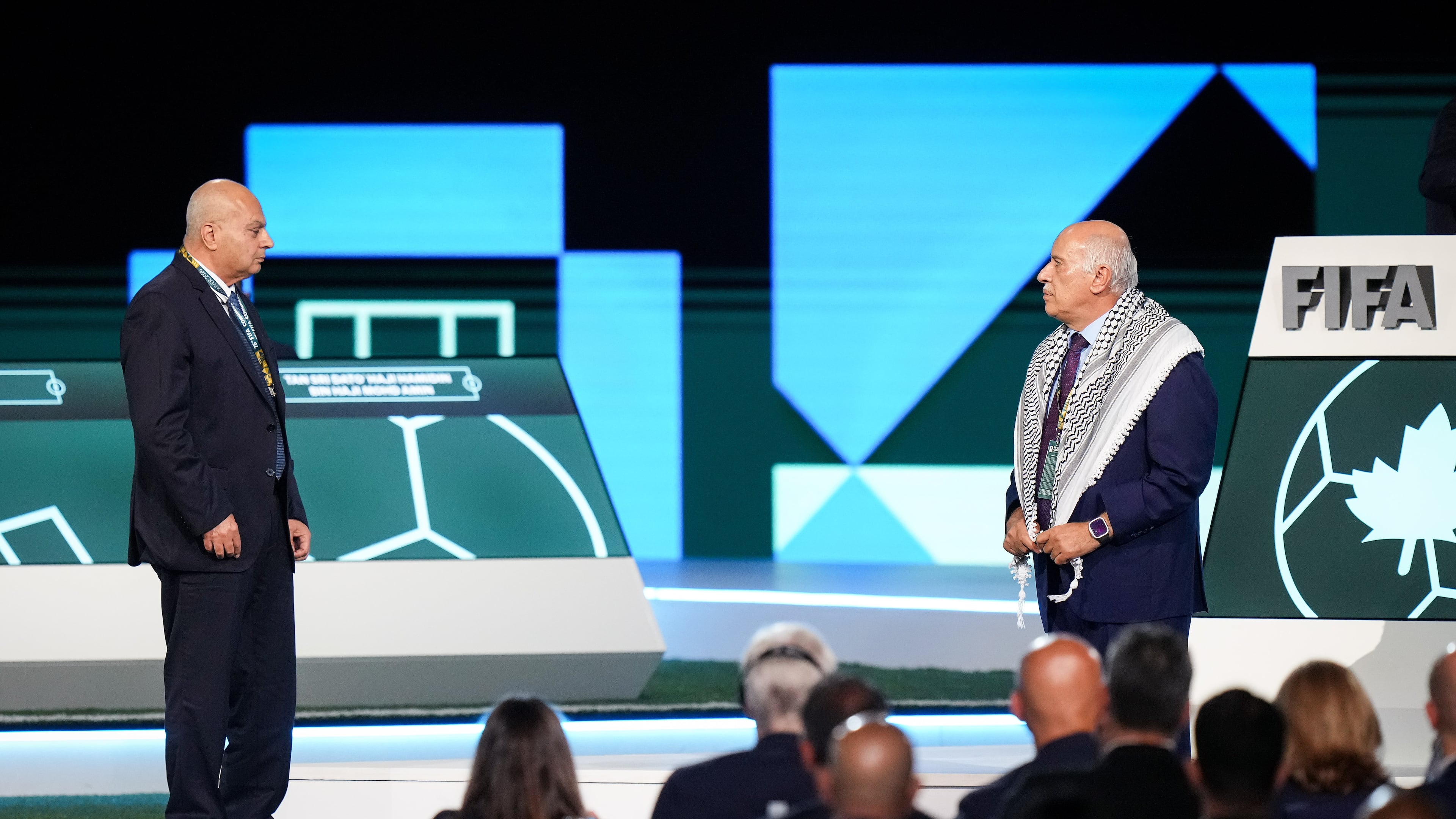Palestinian Football Association President Jibril Rajoub, right, refuses to stand together with Israel Football Association Vice-President Basim Sheikh Suliman, left, after FIFA President Gianni Infantino, not seen, tried to bring them together during the 76th FIFA Congress in Vancouver, British Columbia, Thursday, April 30, 2026. (Darryl Dyck/The Canadian Press via AP)