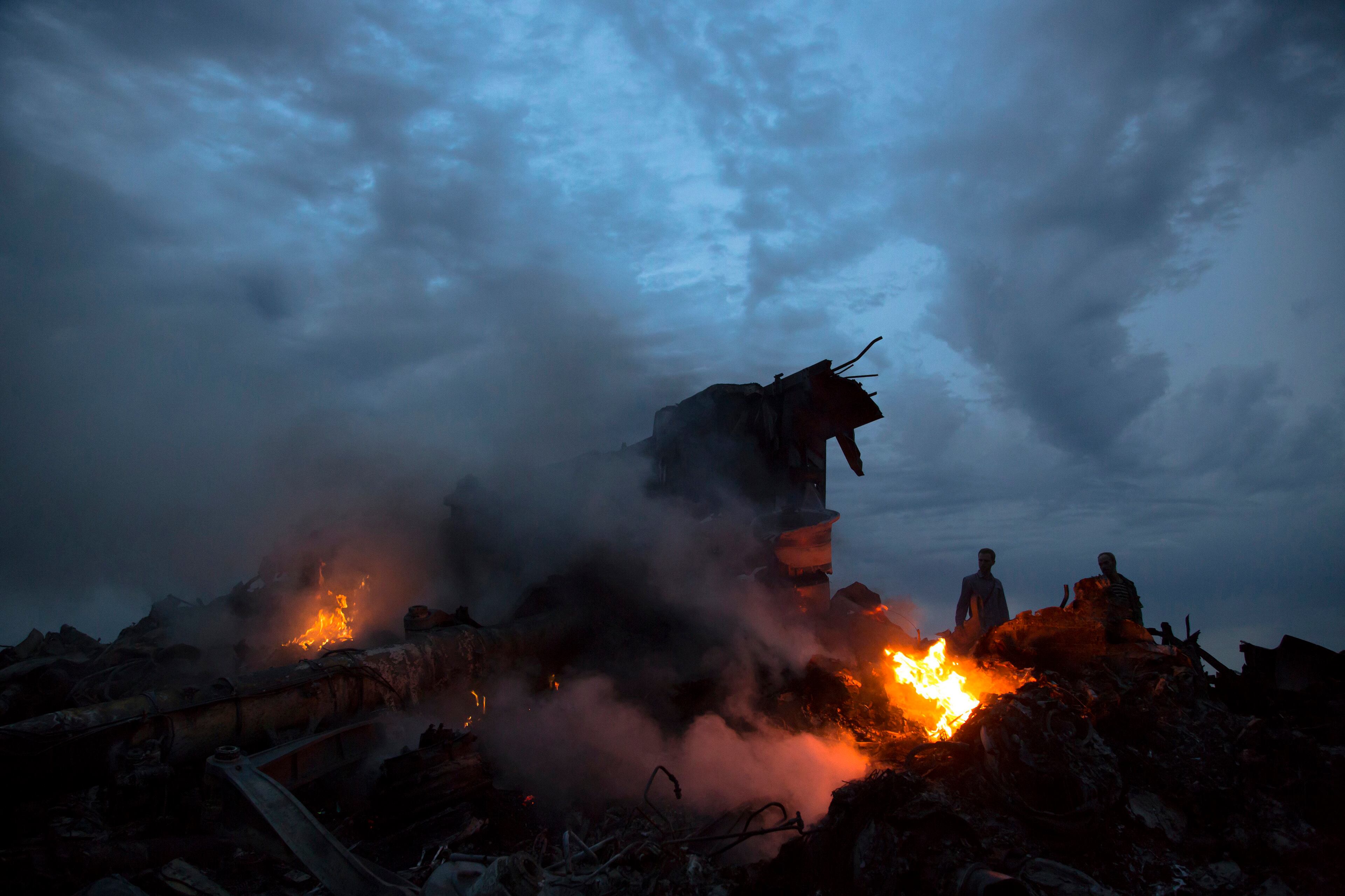 People walk amongst the debris at the crash site of a passenger plane near the village of Grabovo, Ukraine, Thursday, July 17, 2014. Ukraine said a passenger plane carrying 295 people was shot down Thursday as it flew over the country, and both the government and the pro-Russia separatists fighting in the region denied any responsibility for downing the plane. (AP Photo/Dmitry Lovetsky)