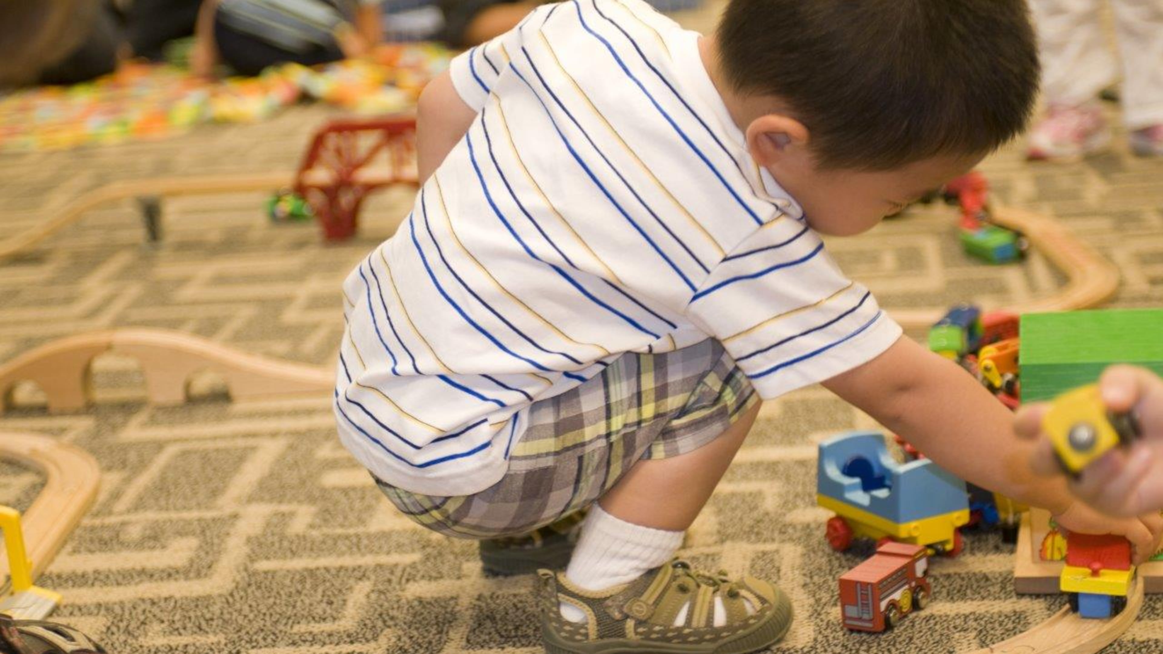 While in a daycare setting, this young boy was entertaining himself by playing with a small wooden toy car set, pushing the little cars along the grooved wooden track. CDC HANDOUT