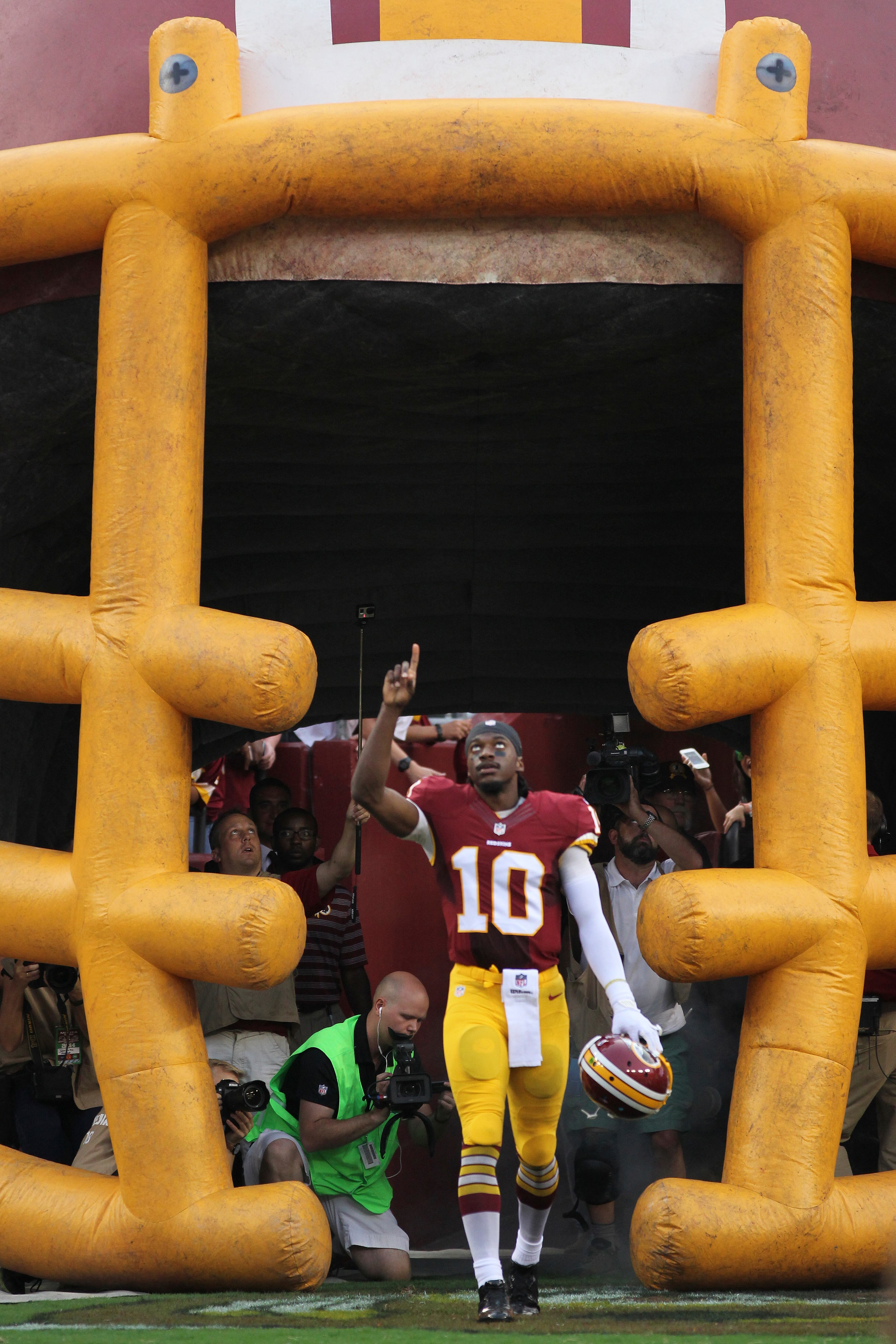 Washington Redskins quarterback Robert Griffin III points skyward during his introduction before the first half of an NFL football preseason game against the New England Patriots in Landover, Md., Thursday, Aug. 7, 2014. (AP Photo/Connor Radnovich)
