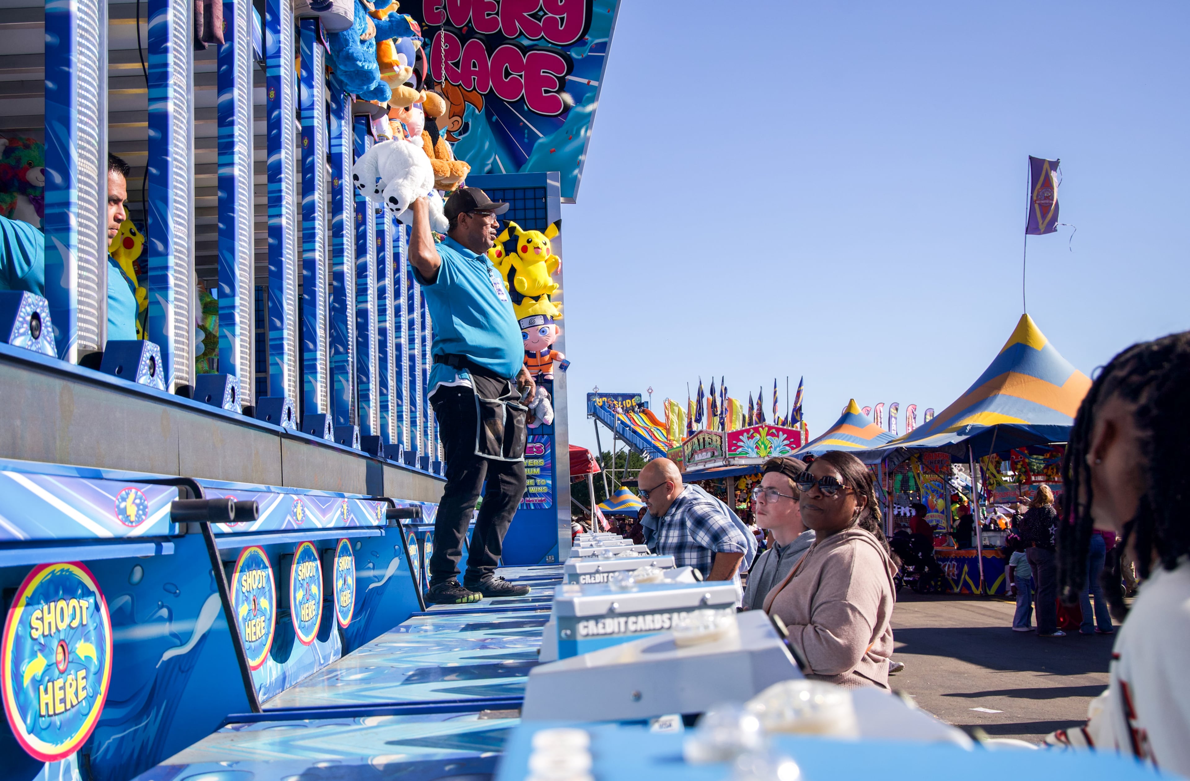 Al McFadden throws a prize to a participant playing the water race game at the Georgia National Fair in Perry, Georgia, on Oct. 17, 2026. McFadden operated the game with Luis Martinez. (Emily Laycock/UGA Photojournalism Workshop)