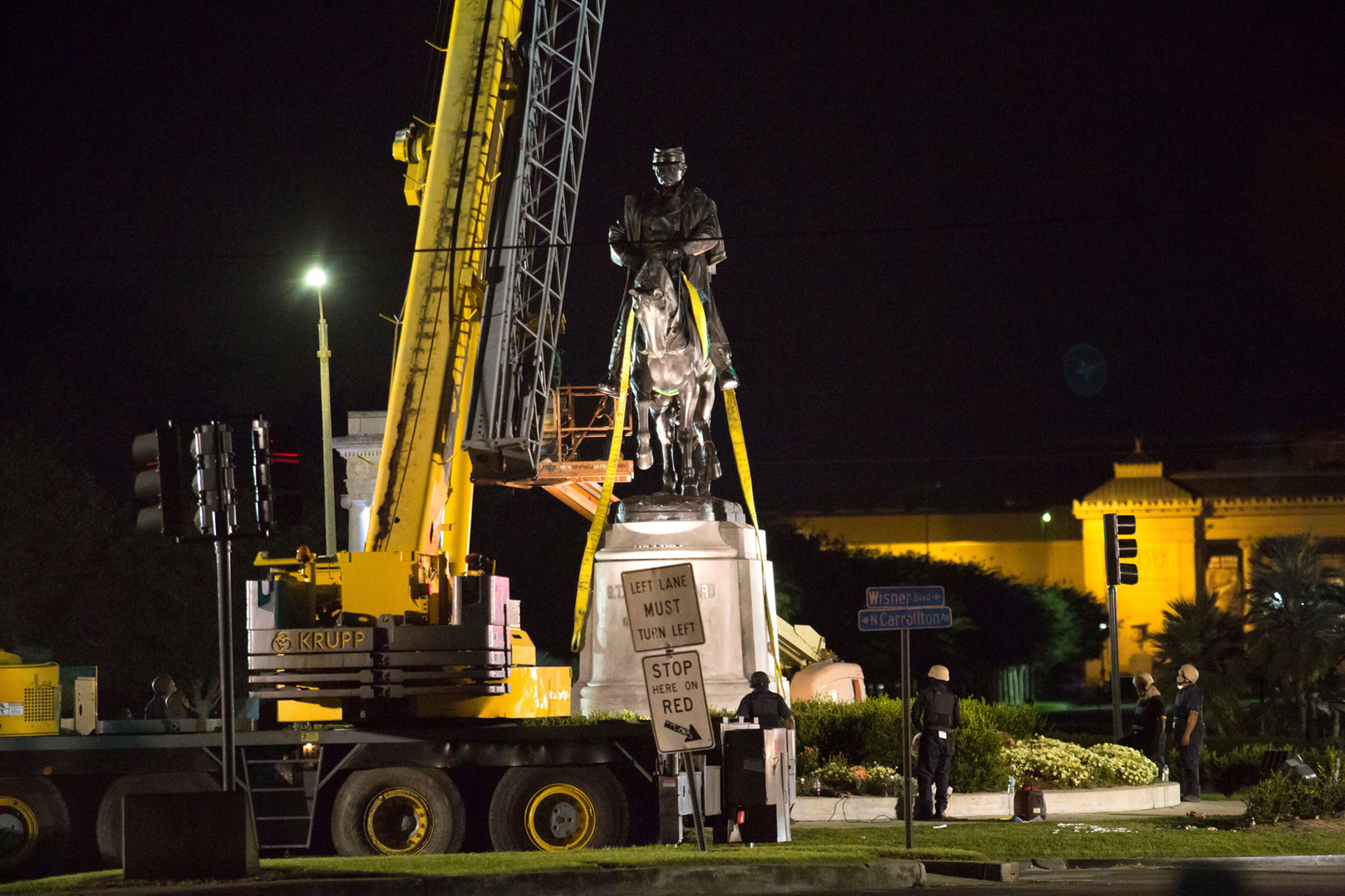 Workers in protective gear attach straps to the statue of Confederate general P.G.T. Beauregard Tuesday, May 16, 2017, as it is prepared for removal from the entrance to City Park in New Orleans. The statue came down just after 3 a.m. Central Standard Time Wednesday. The city council voted to remove the monument and three other Confederate and white supremacist monuments in Dec. 2015. An obelisk honoring the militia known as the White League was taken down in April, and a statue of Jefferson Davis was removed May 11. No date has been set for the removal of the Robert E. Lee statue in Lee Circle.(AP Photo/Scott Threlkeld)