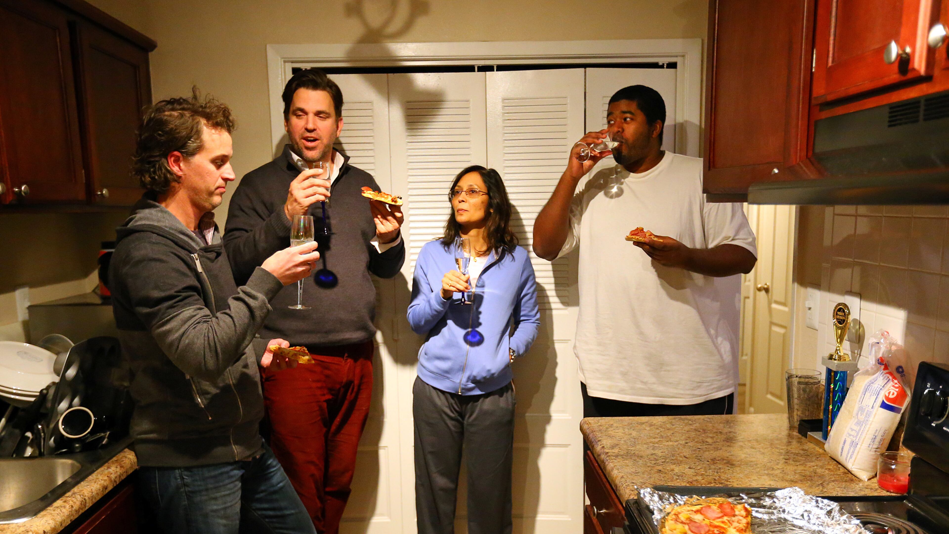 Daniel Ringenberg (from left), Conn Jackson, Rebecca Ganguly and Etienne Bertie share a meal of pizza and sparkling water in Jackson's kitchen on Wednesday night, Jan. 29, 2014. Jackson took 10 strangers into his Vinings apartment during the snowstorm and kept three of them a second day.