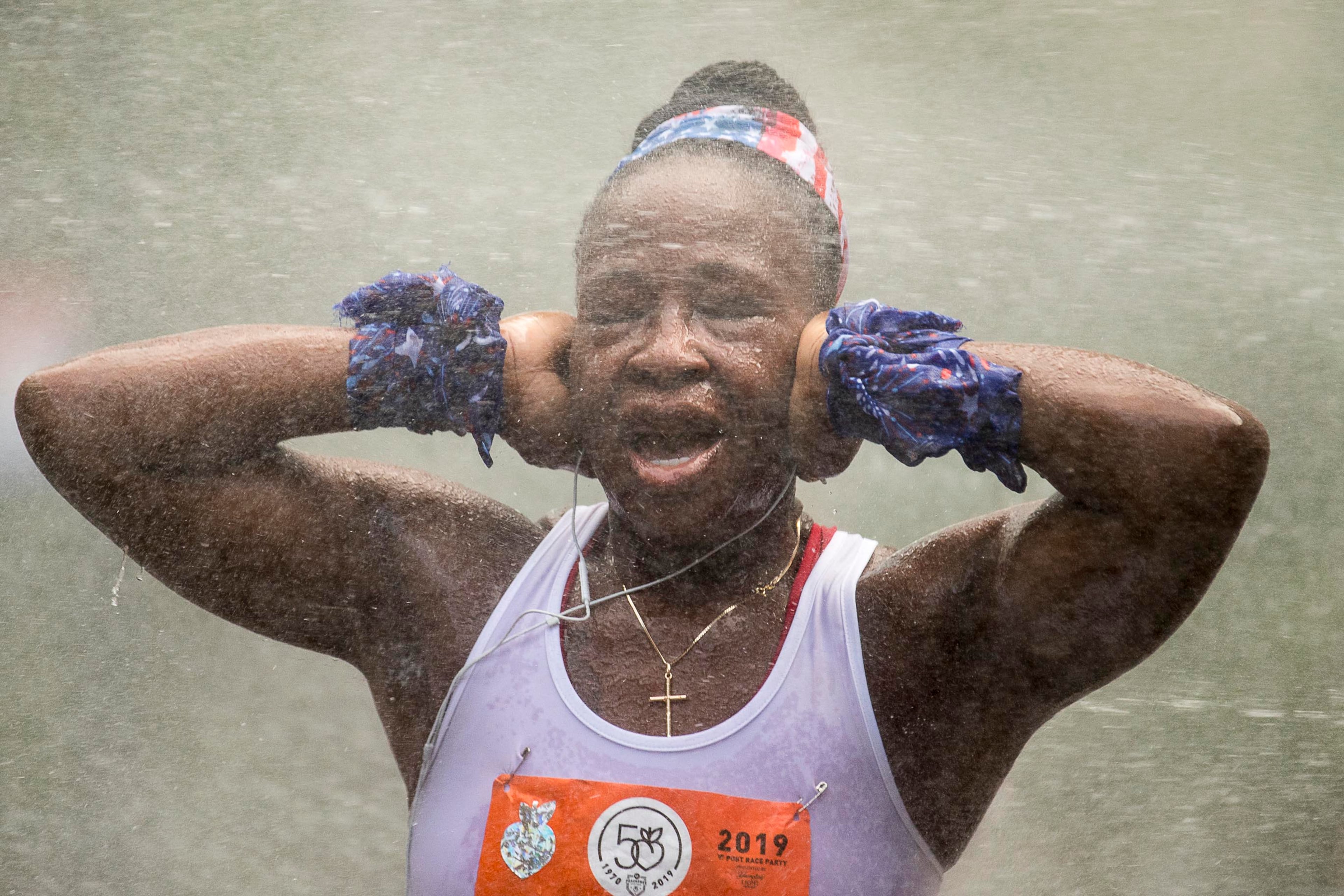 A runner is sprayed by a mist machine during the AJC Peachtree Road Race in Atlanta, Thursday, July 4, 2019. (Alyssa Pointer/alyssa.pointer@ajc.com)