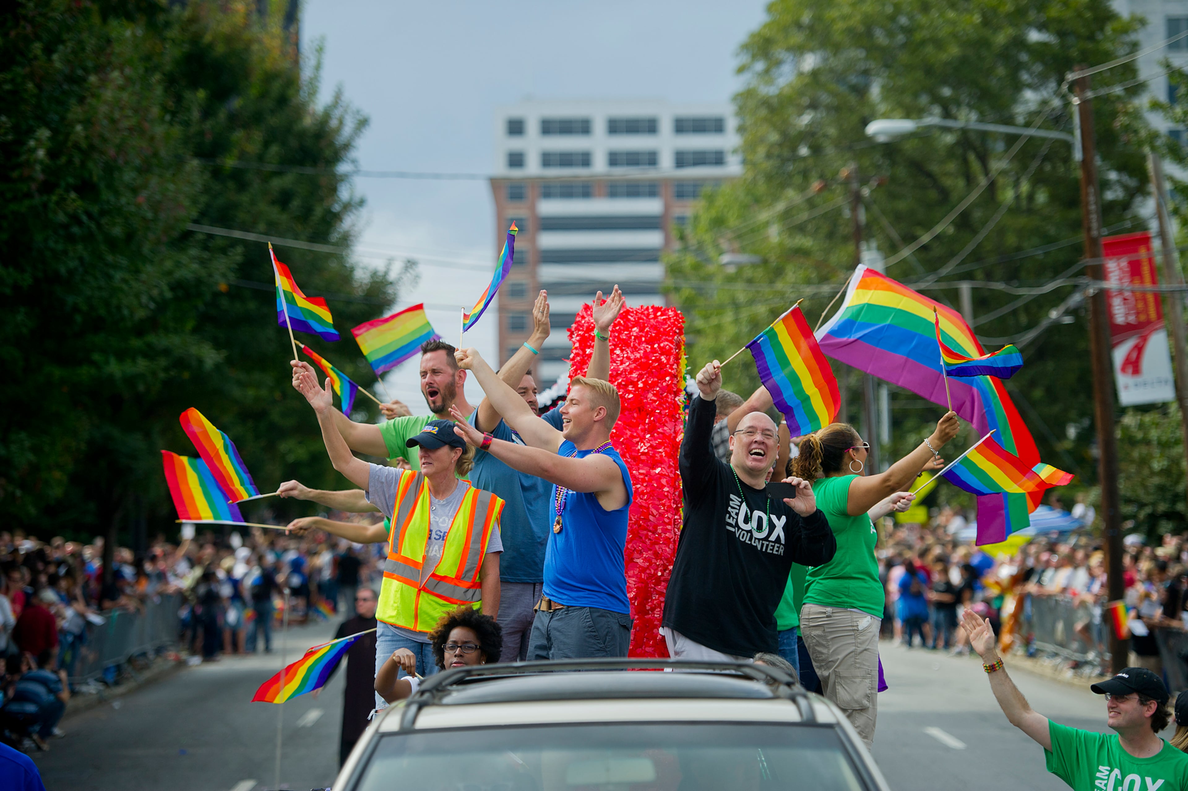 Erin Frederickson (left), Will Johnston and David Tow wave to the crowds of people on 10th Street during the Atlanta Pride Parade on Sunday, Oct. 14, 2012. Thousands of people came out to watch the parade that wound its way through downtown and ended in Piedmont Park.