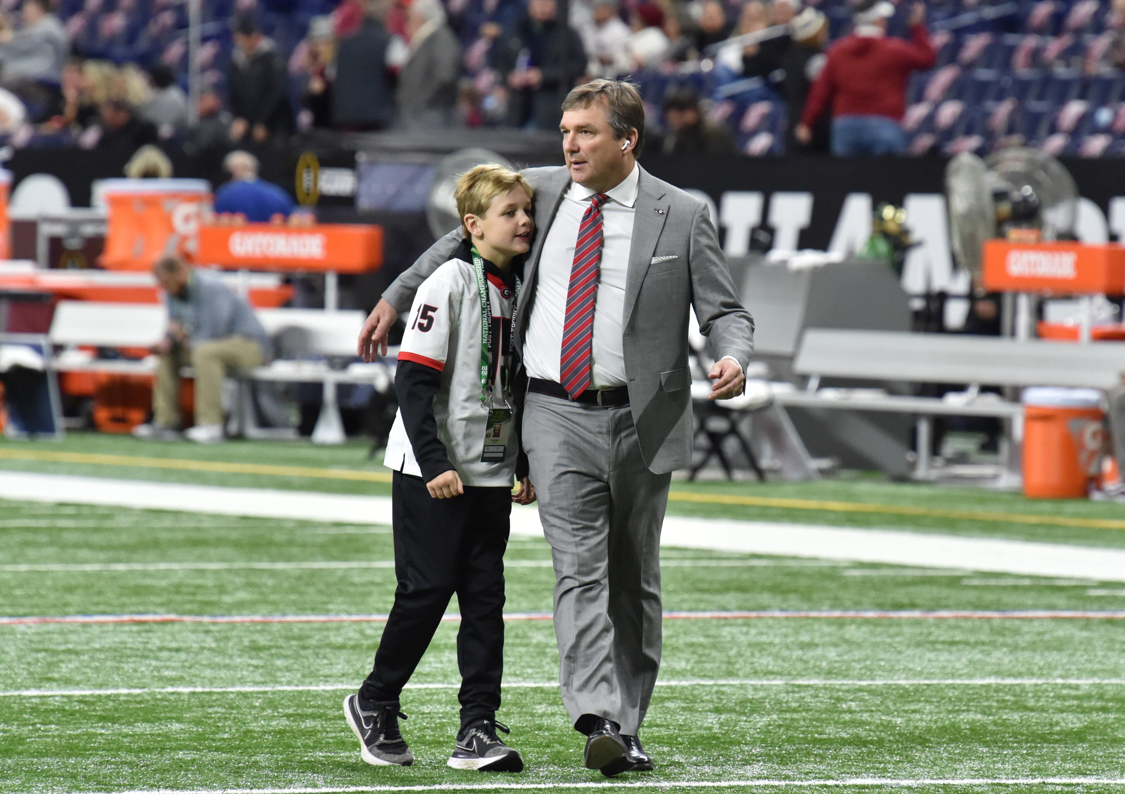 Georgia's head coach Kirby Smart hugs his son his son Andrew as he walks on the football field prior to the 2022 College Football Playoff National Championship Game against Alabama at Lucas Oil Stadium in Indianapolis on Monday, January 10, 2022. (Hyosub Shin / Hyosub.Shin@ajc.com)