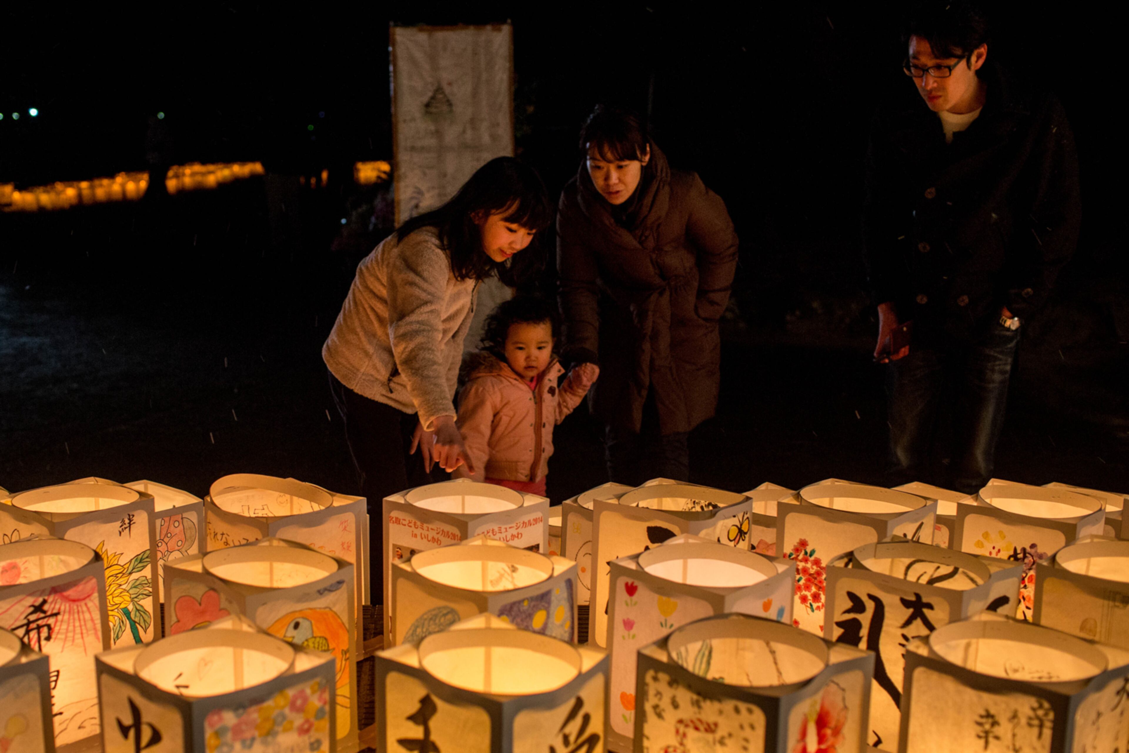 TSUNAMI ANNIVERSARY--NATORI, JAPAN - MARCH 11: People look at paper lanterns during a memorial service for tsunami victims at the Yuriage Junior High School on March 11, 2015 in Natori, Japan. On March 11 Japan commemorates the fourth anniversary of the magnitude 9.0 earthquake and tsunami that claimed more than 18,000 lives, and subsequent nuclear disaster at the Fukushima Daiichi Nuclear Power Plant. (Photo by Chris McGrath/Getty Images)