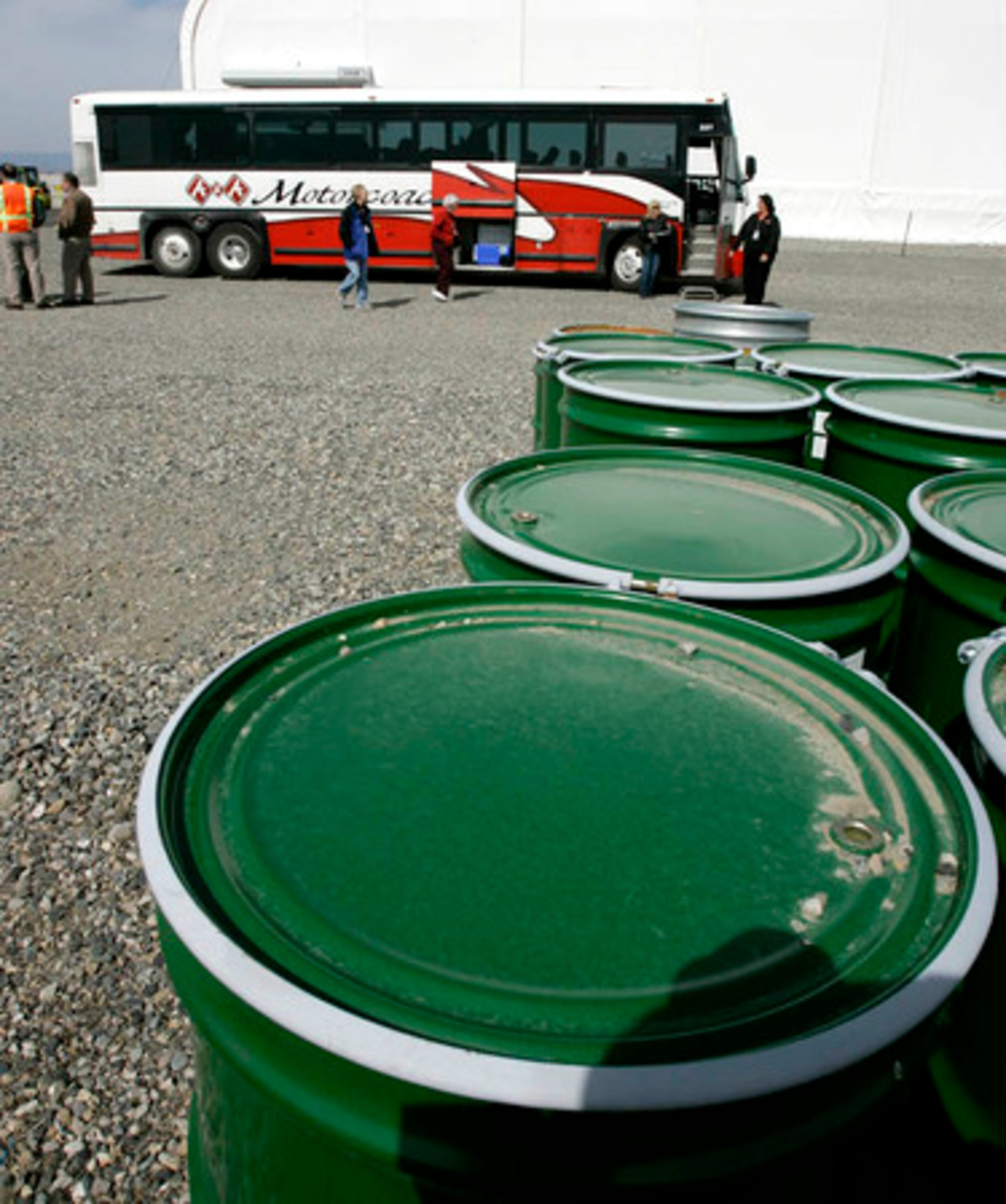 New barrels that will be used to hold radioactive materials in less sturdy containers dug up on the Hanford nuclear reservation sit near a tour bus. About 53 million gallons of toxic radioactive waste -- enough to cover 123 football fields, including end zones, a foot deep -- sit stewing in 177 aging underground tanks.