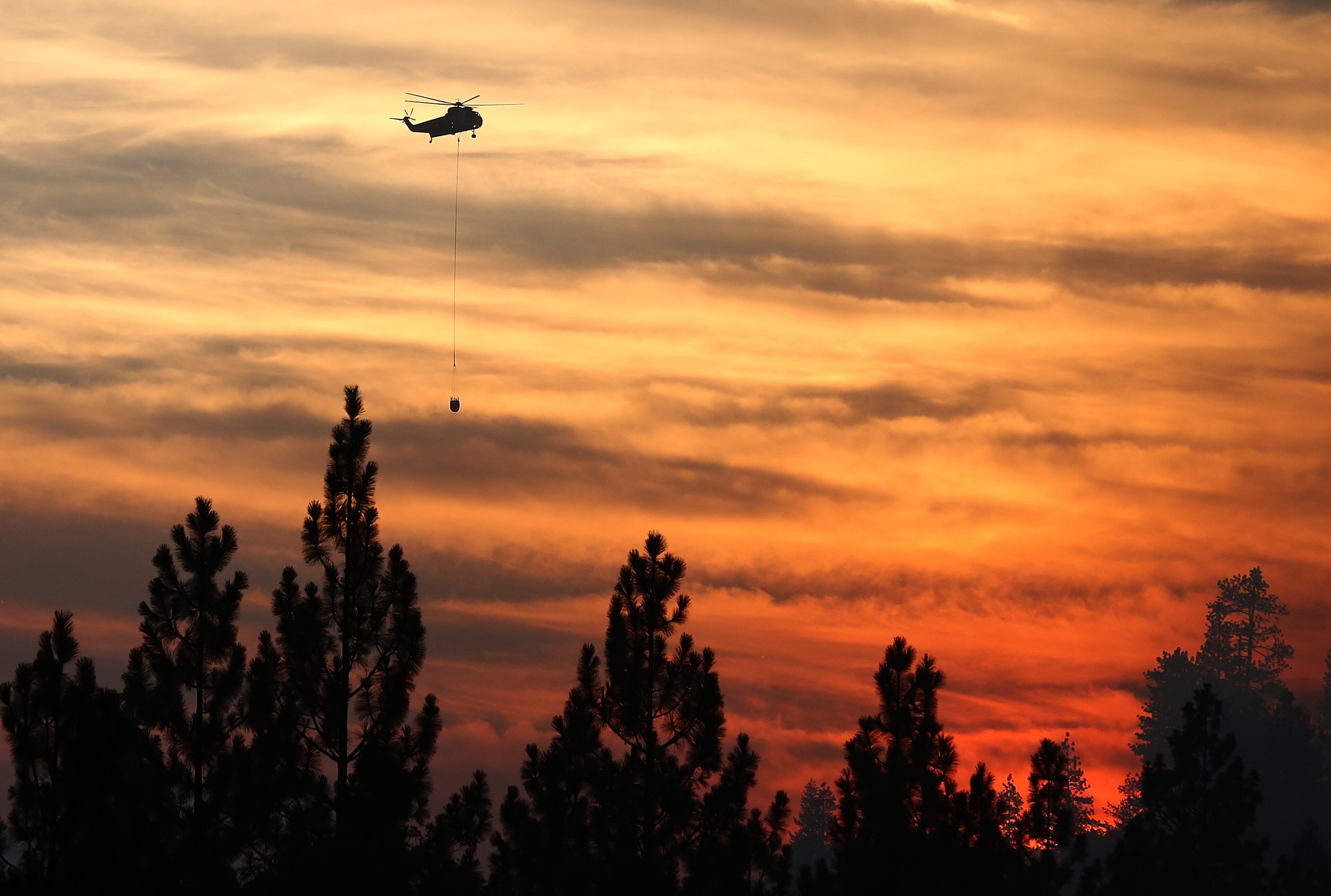 GROVELAND, CA - AUGUST 24: A firefighting helicopter prepares to drop water on the Rim Fire on August 24, 2013 near Groveland, California. The Rim Fire continues to burn out of control and threatens 4,500 homes outside of Yosemite National Park. Over 2,000 firefighters are battling the blaze that has entered a section of Yosemite National Park and is currently 5 percent contained. (Photo by Justin Sullivan/Getty Images)