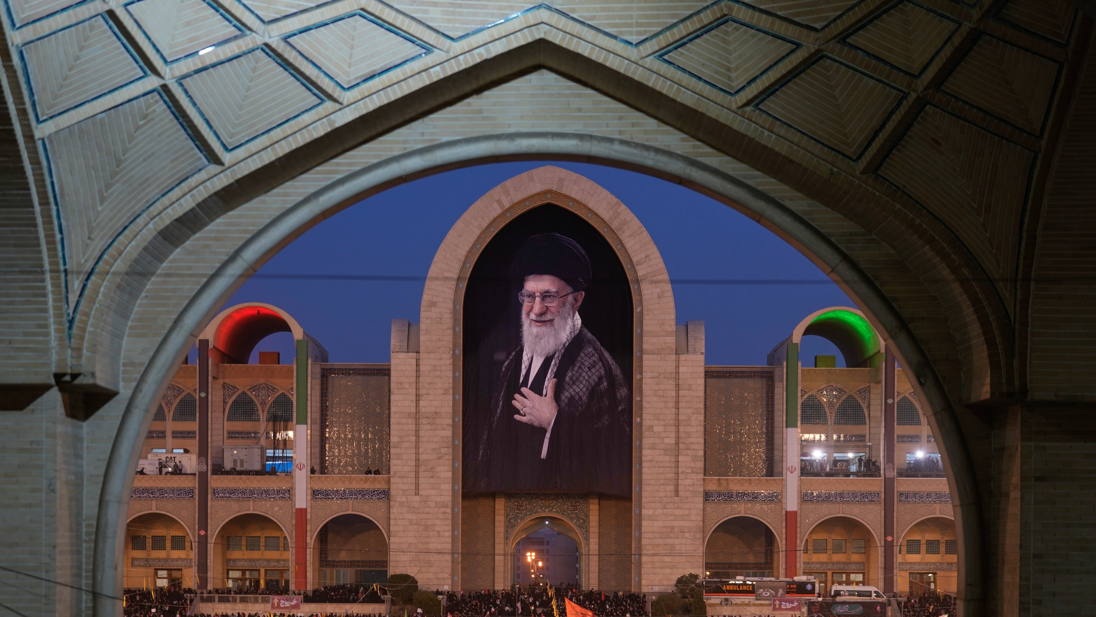 Mourners gather beneath a portrait of the late Iranian Supreme Leader Ayatollah Ali Khamenei during the funeral ceremonies for Khamenei and members of his family at the Imam Khomeini Mosalla Grand Mosque in Tehran, Iran, Saturday, July 4, 2026. (AP Photo/Altaf Qadri)
