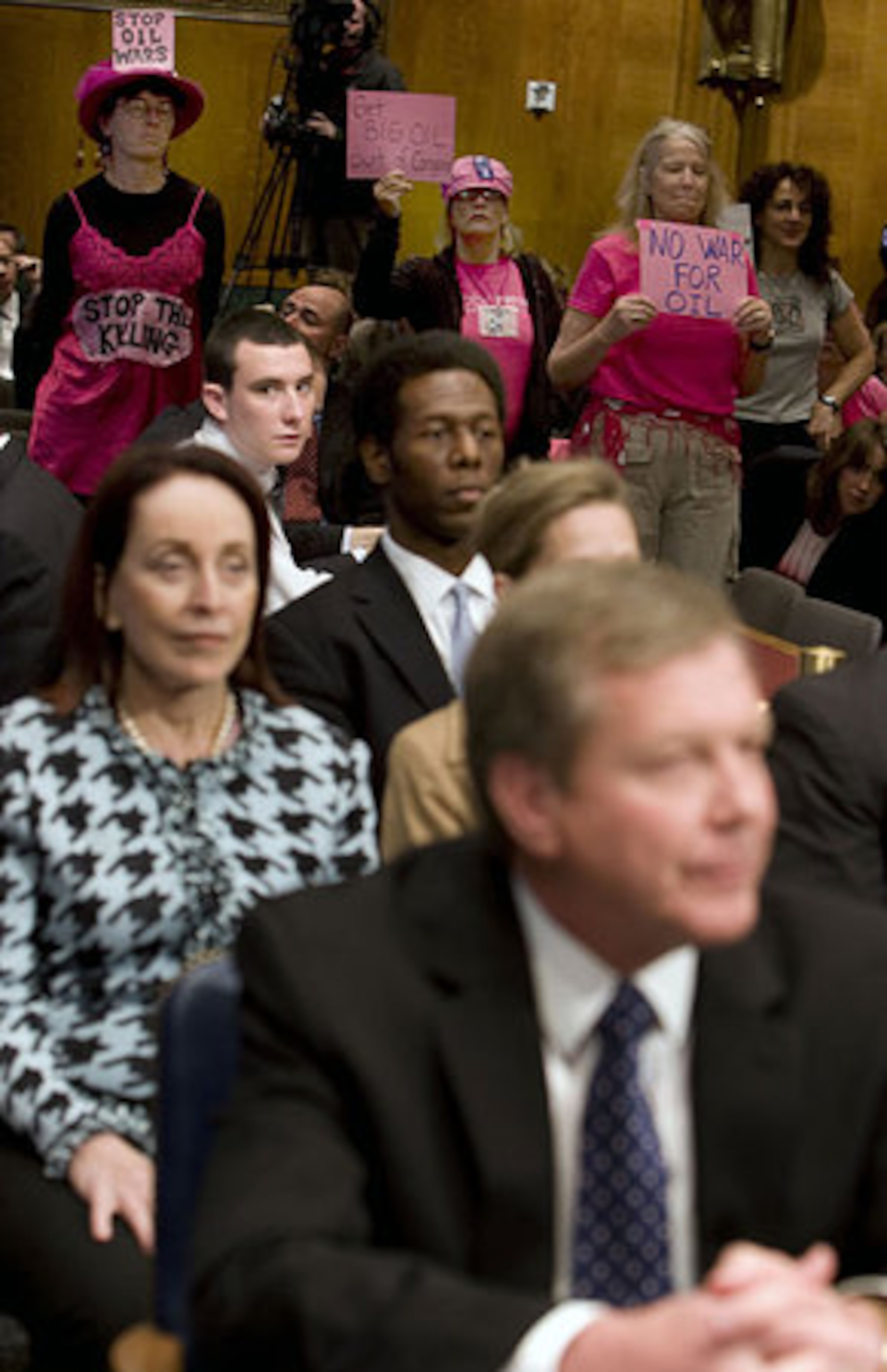 Members of Code Pink stand in protest at the start of the Senate Judiciary Committee hearing on ''Exploring the Skyrocketing Price of Oil'' Wednesday, May 21, 2008. Seated in the foreground is Robert Malone, chairman and president of BP America Inc.