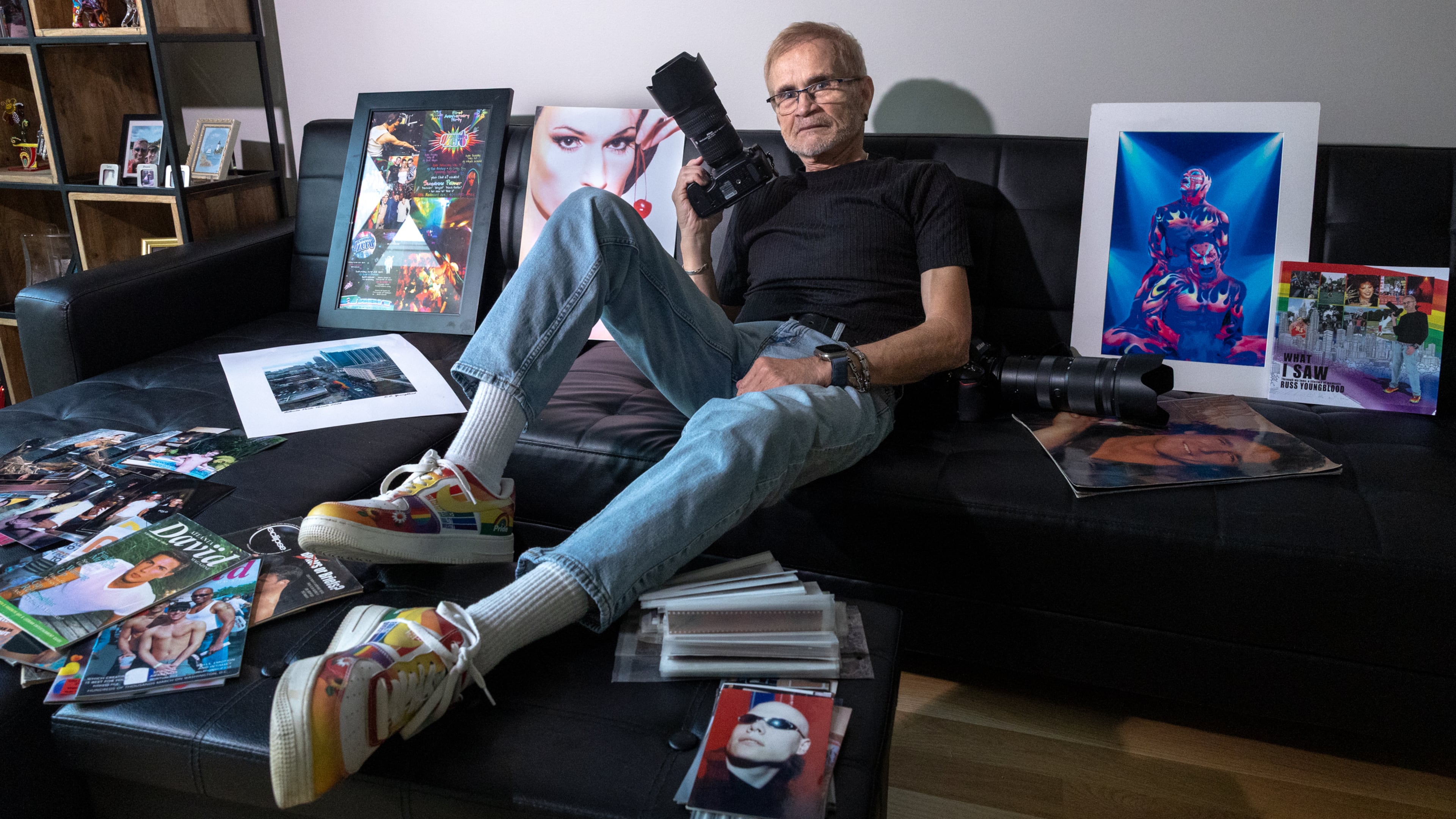 Photographer Russ Youngblood, who has documented the gay community for decades, poses for a portrait with some of his prints, magazine covers and film negatives at his home in Atlanta on Oct. 8, 2026. (Arvin Temkar/AJC)