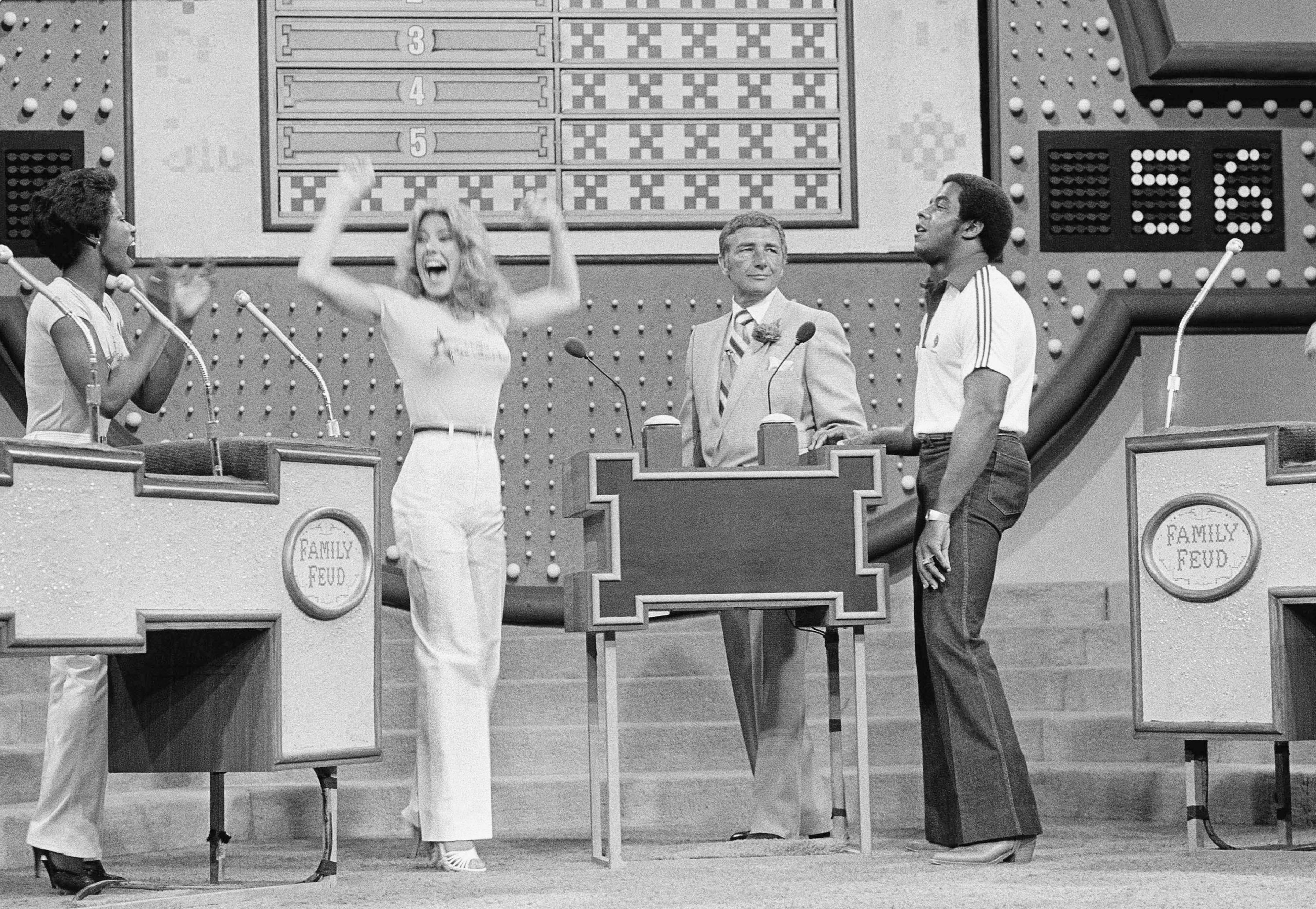 In this June 25, 1980 file photo, as host Richard Dawson, center, watches, Dallas Cowboys running back Tony Dorsett, right, grimaces, and Cowboys cheerleader Suzette Scholz-Derrick waves happily after Suzette beat Dorsett with a correct answer during taping of the "Family Feud" game show at ABC television studios in Los Angeles. (Randy Rasmussen/AP)