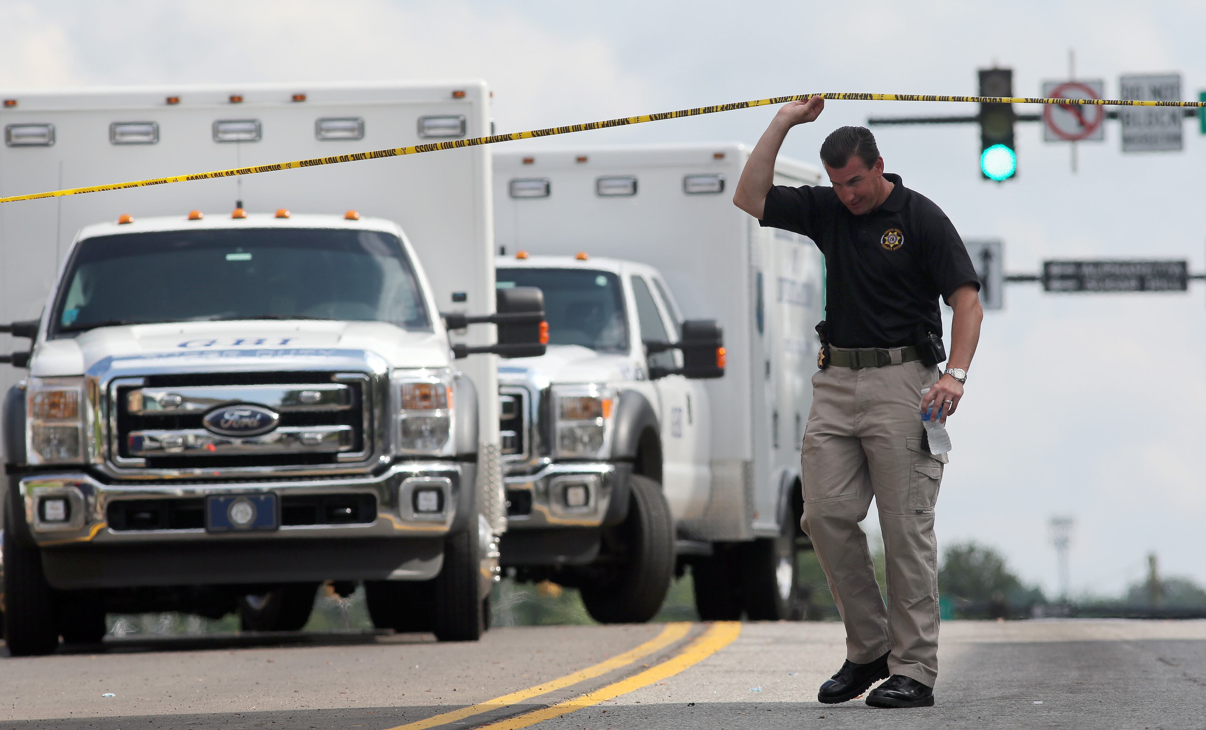 A member of the Forsyth Sheriff's Department ducks under crime scene tape near the Forsyth County Courthouse in Cumming on Friday afternoon June 6, 2014 following a morning shoot out that left one deputy injured and the perpetrator dead.