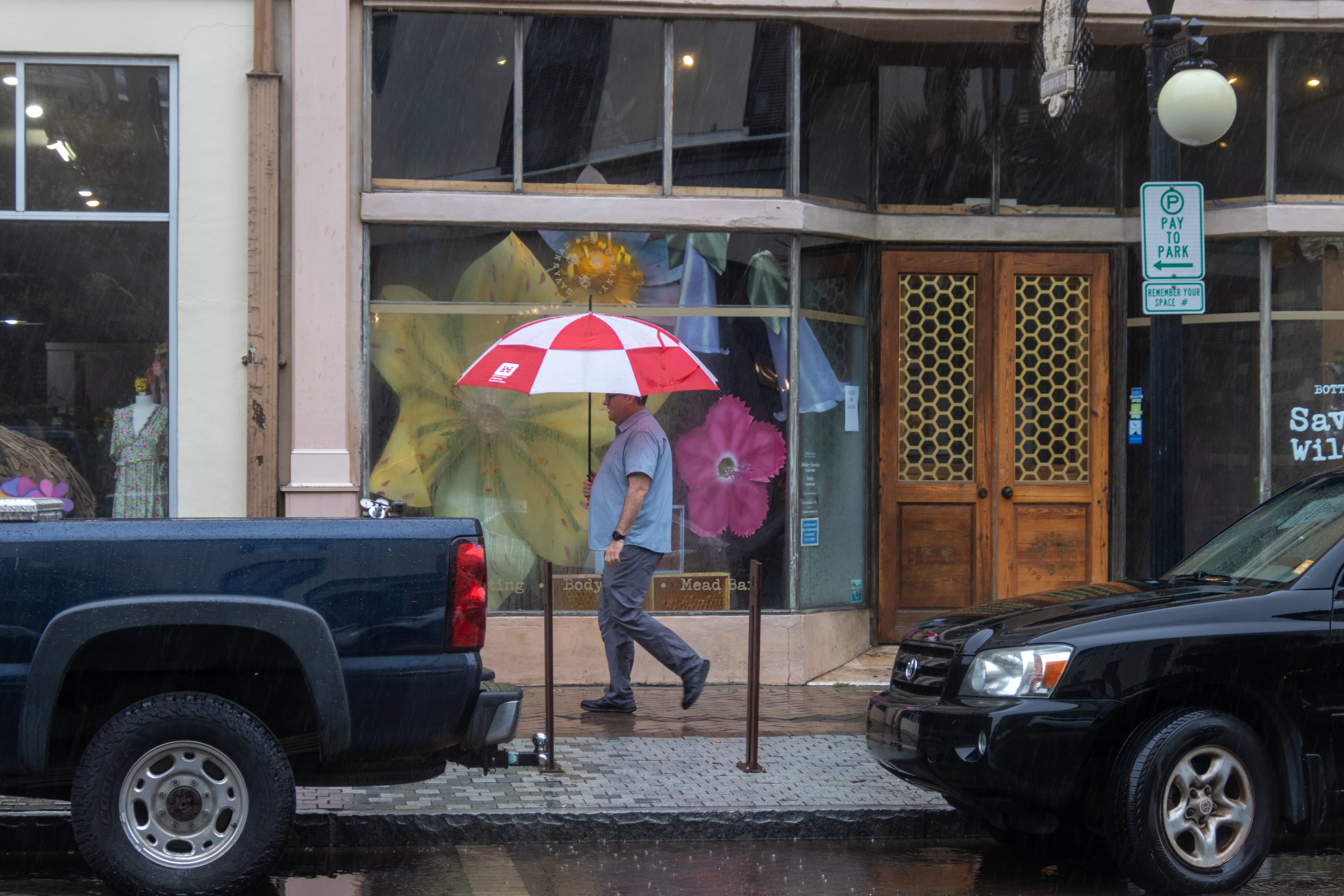 A person walks on Broughton street with an umbrella on Monday, August 5, 2024 in Savannah, GA. (AJC Photo/Katelyn Myrick)