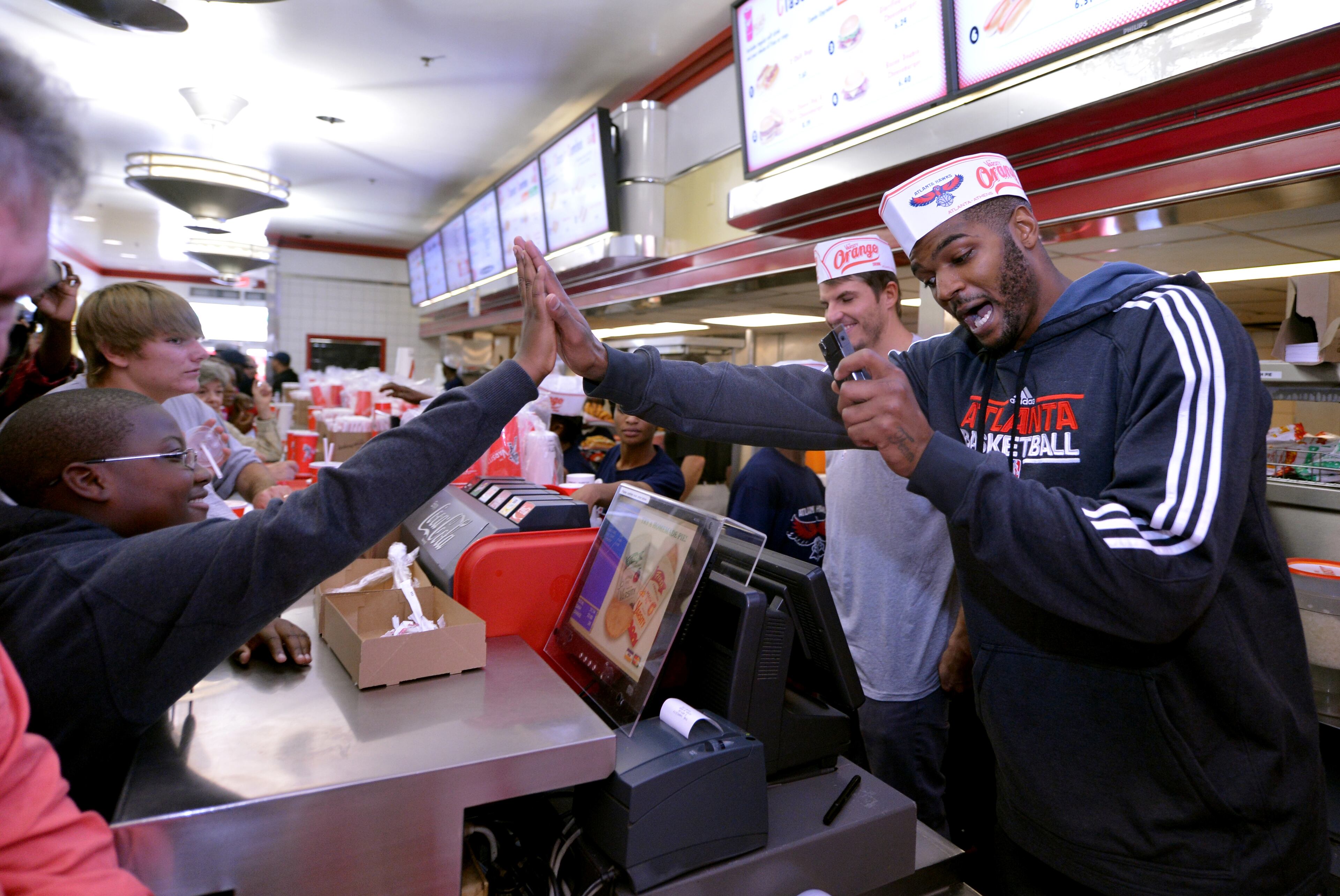 Smith exchanges a high-five with customer Justin Amado while guard Kyle Korver looks on.