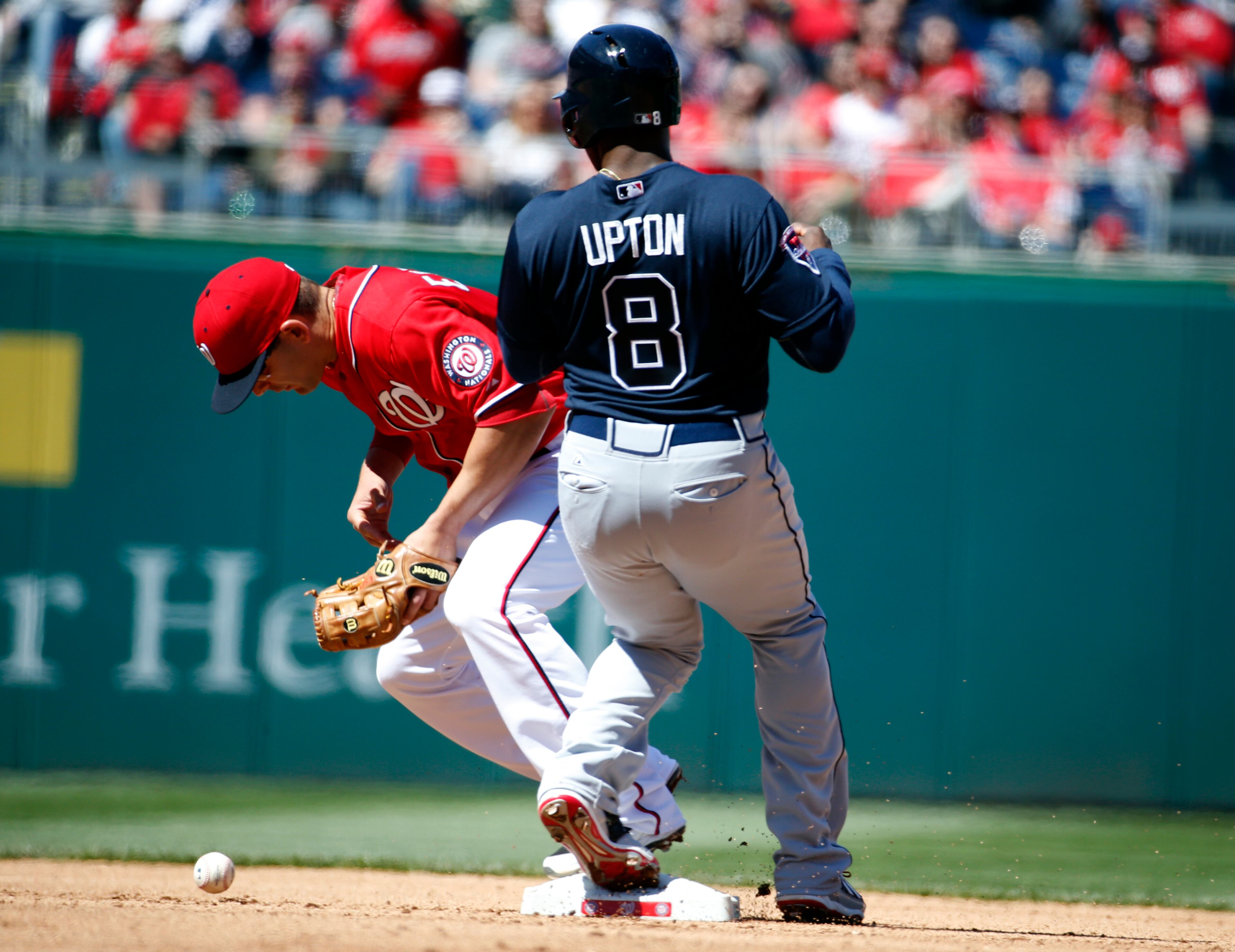 Washington Nationals second baseman Danny Espinosa, left, cannot handle the throw as Atlanta Braves' Justin Upton, right, is safe at second on a hit by Dan Uggla during the fourth inning of a baseball game at Nationals Park, Sunday, April 6, 2014, in Washington. (AP Photo/Alex Brandon)
