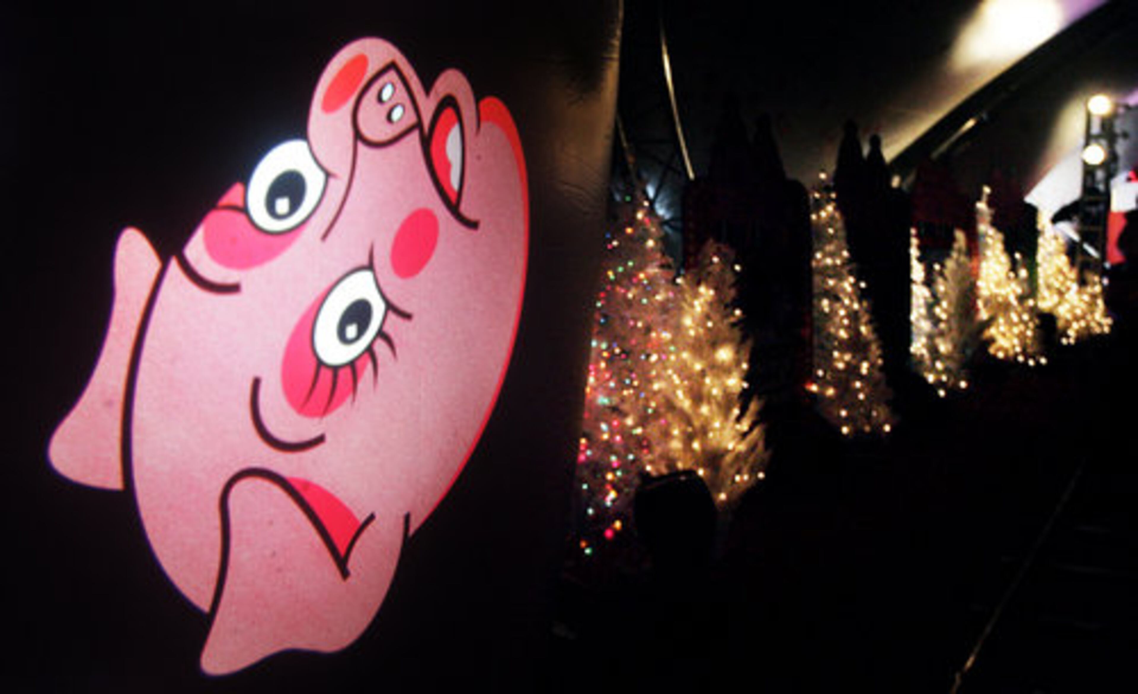 A projection of a pig's head spins near a row of Christmas trees. A portion of the ride's proceeds will benefit Children's Healthcare of Atlanta.