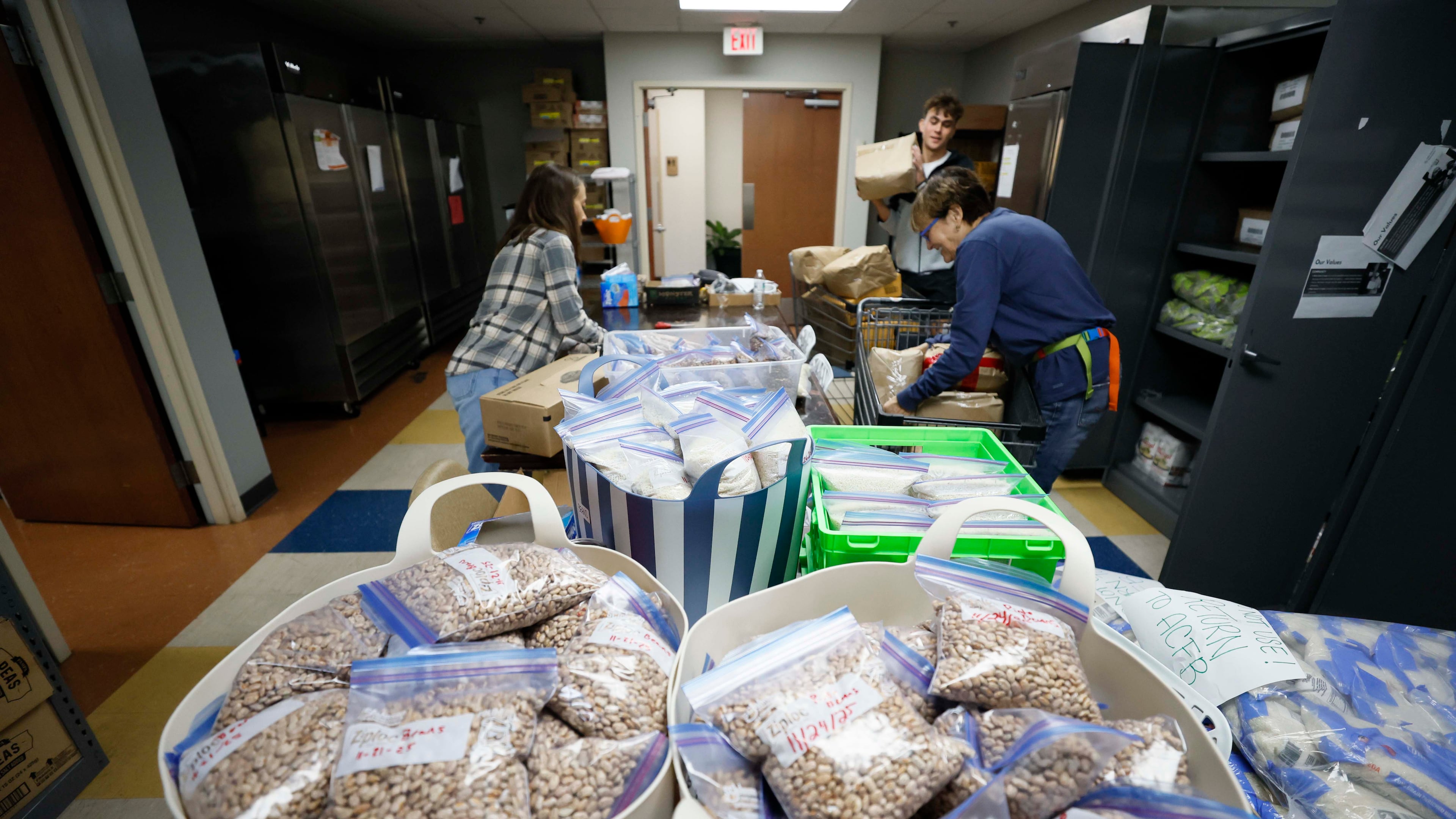 Volunteers with the Latin American Association — including Ellen Goldwasser (left), Nick Nele (center) and Ellen Levitt — are seen organizing boxes and bags of food in 2025. The organization is dedicated to empowering individuals and families through education, workforce development, immigration services and community engagement. (Miguel Martinez/AJC)