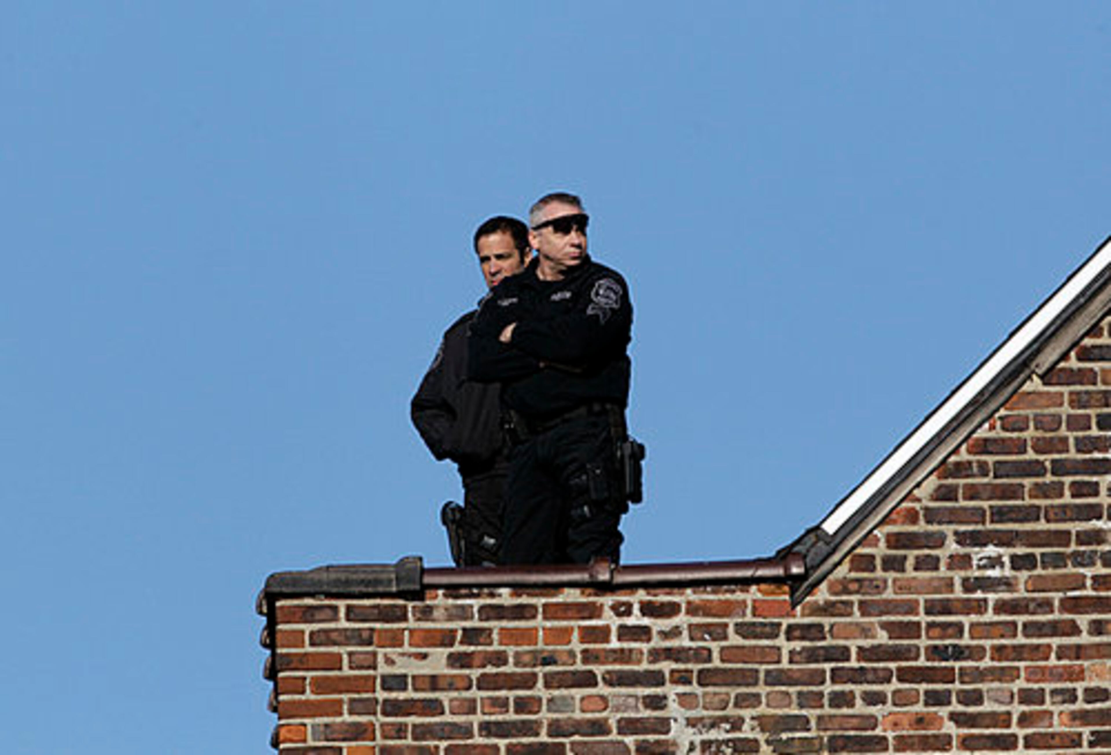 Police officers stand on a roof near the New Hope Baptist Church before funeral services there for singer Whitney Houston in Newark, N.J., Saturday, Feb. 18, 2012.
