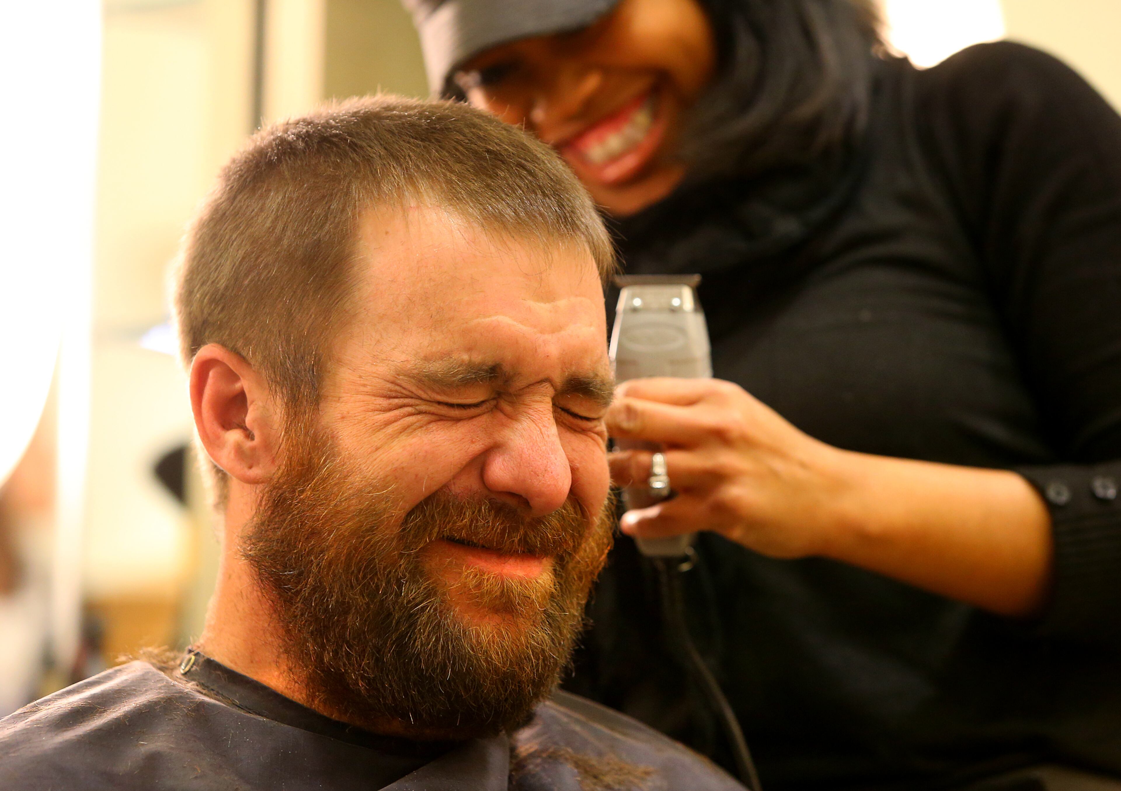 Nesha Lewis has Joel Hartman, the "Homeless Hero," squinting his eyes and holding back laughter during his makeover at Nelda's Hair Salon on Nov. 25, 2013, in Atlanta.