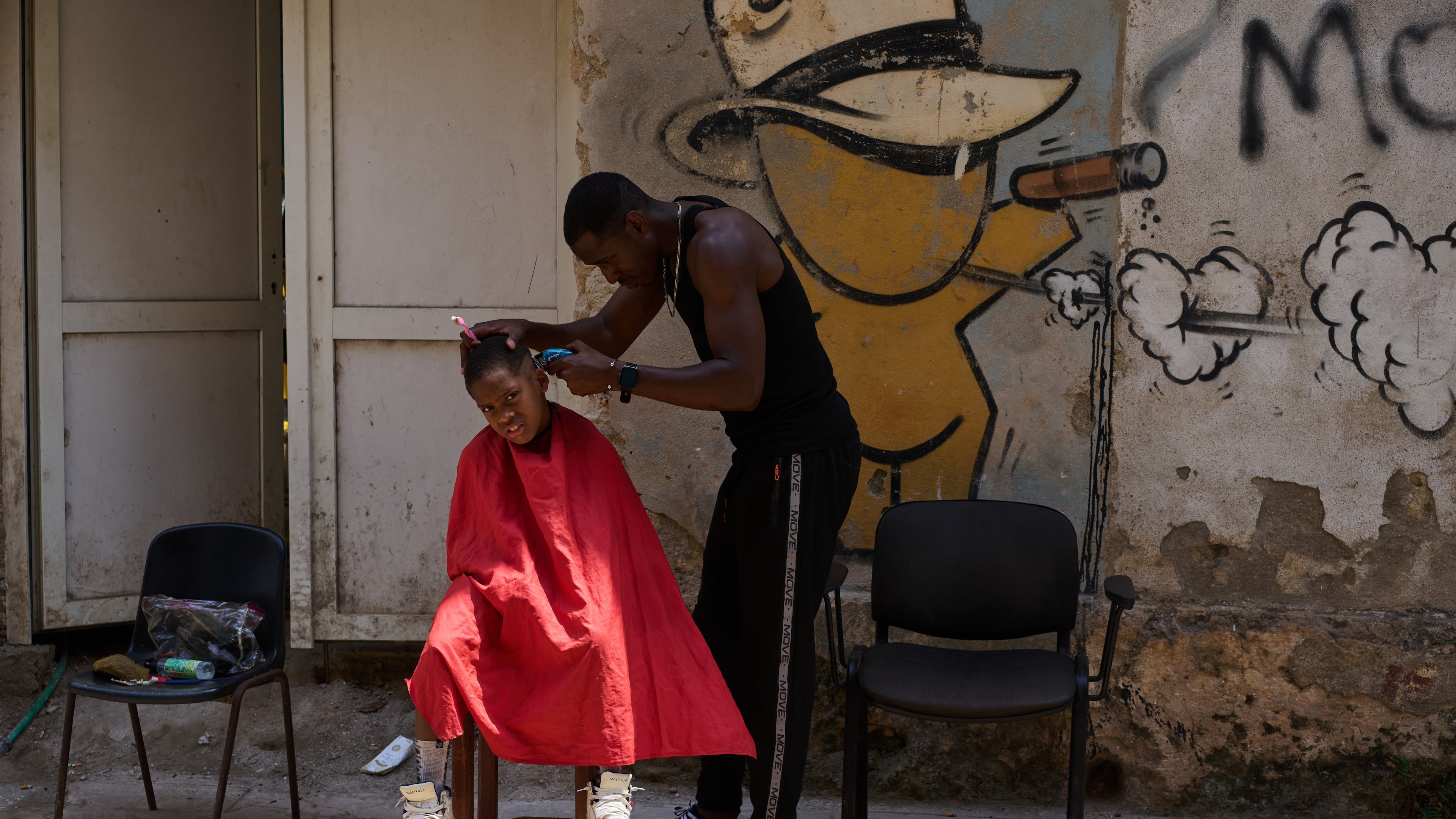 A barber cuts a boy's hair at his makeshift barbershop on the street in Havana, Wednesday, April 22, 2026. (AP Photo/Ramon Espinosa)