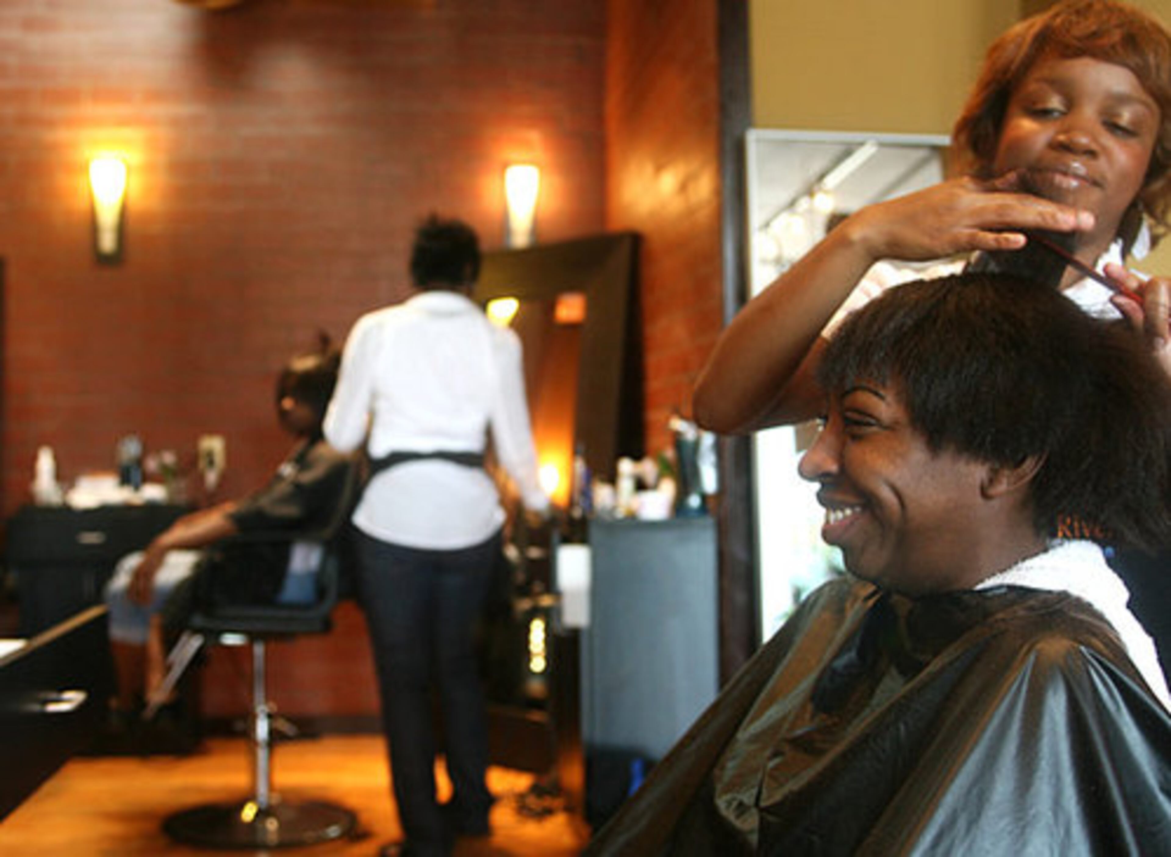 Latricia Johnson smiles as stylist Carlisa "CJ" Neal cuts her hair. "It is all about self-esteem," Johnson said.