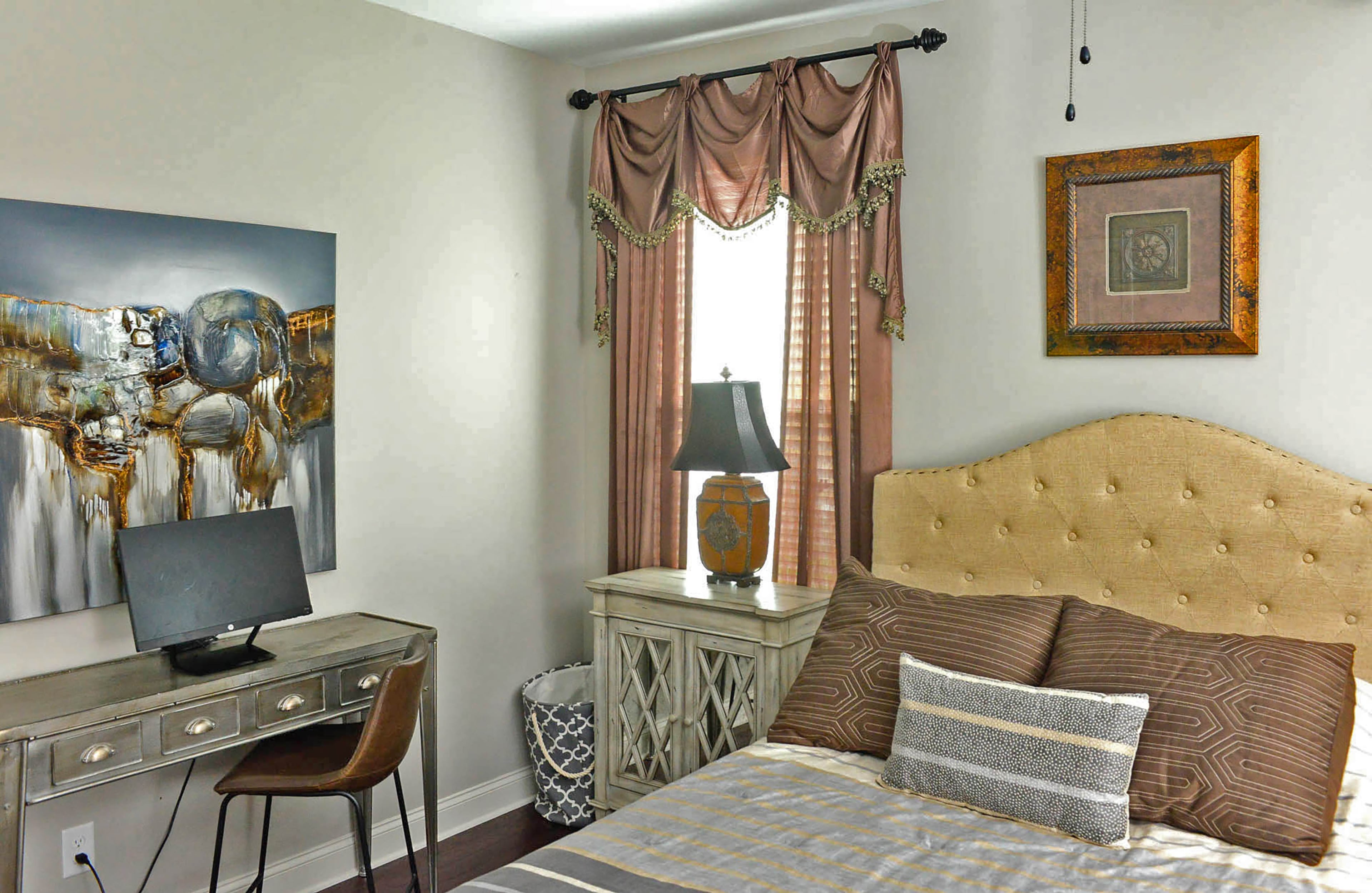 One of three bedrooms in the home blends modern and traditional items, from the bold artwork and silver desk from TJMaxx to traditional-style curtains from Bed Bath & Beyond. Throw pillows carry the color from the curtains to the bed, which is softened by the tufted headboard from Kirklands. Text by Lori Johnson and Kelsey E. Green/Fast Copy News Service.
(Christopher Oquendo Photography/www.ophotography.com)