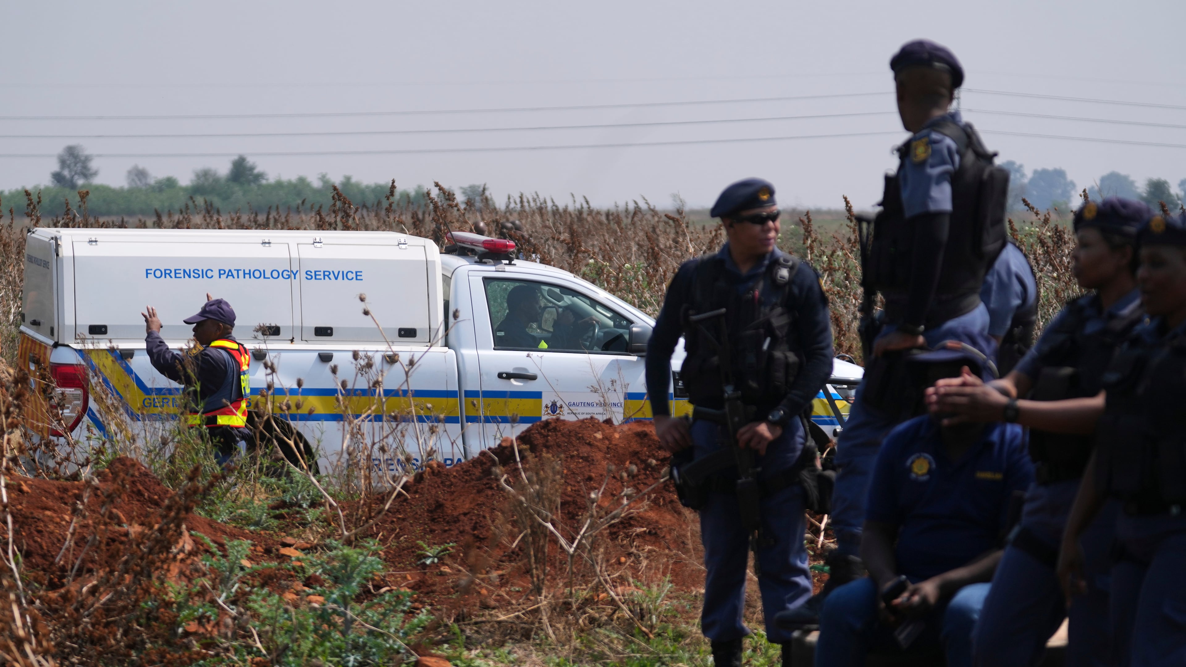 Forensic investigators work at the site where the body of a woman was discovered on the outskirts of Johannesburg, South Africa, Thursday, Sept. 17, 2026. (AP Photo/Themba Hadebe)