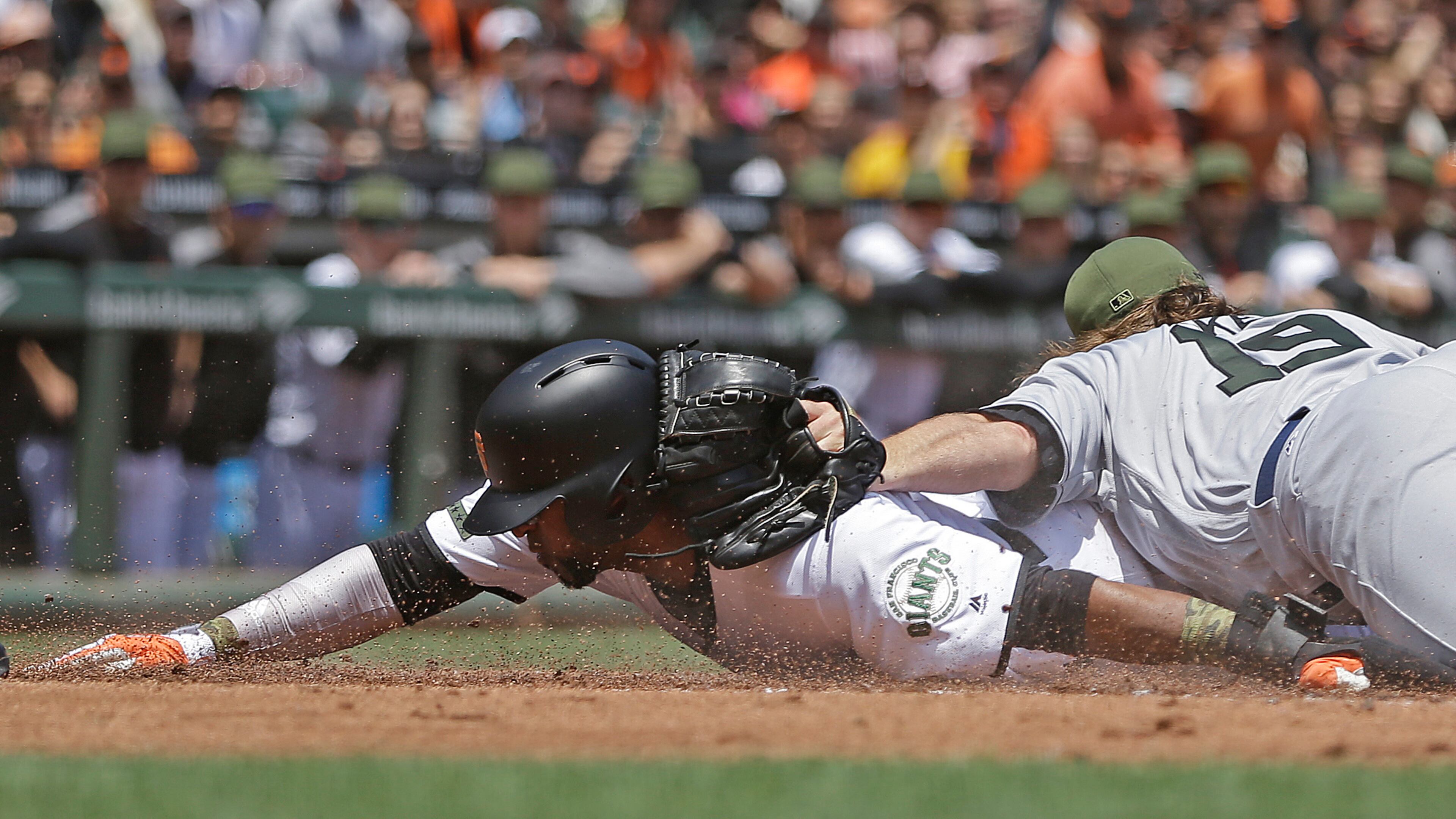 San Francisco Giants’ Eduardo Nunez, left, slides to score on a wild pitch by Atlanta Braves pitcher R.A. Dickey, right, in the first inning Sunday. (AP Photo/Ben Margot)