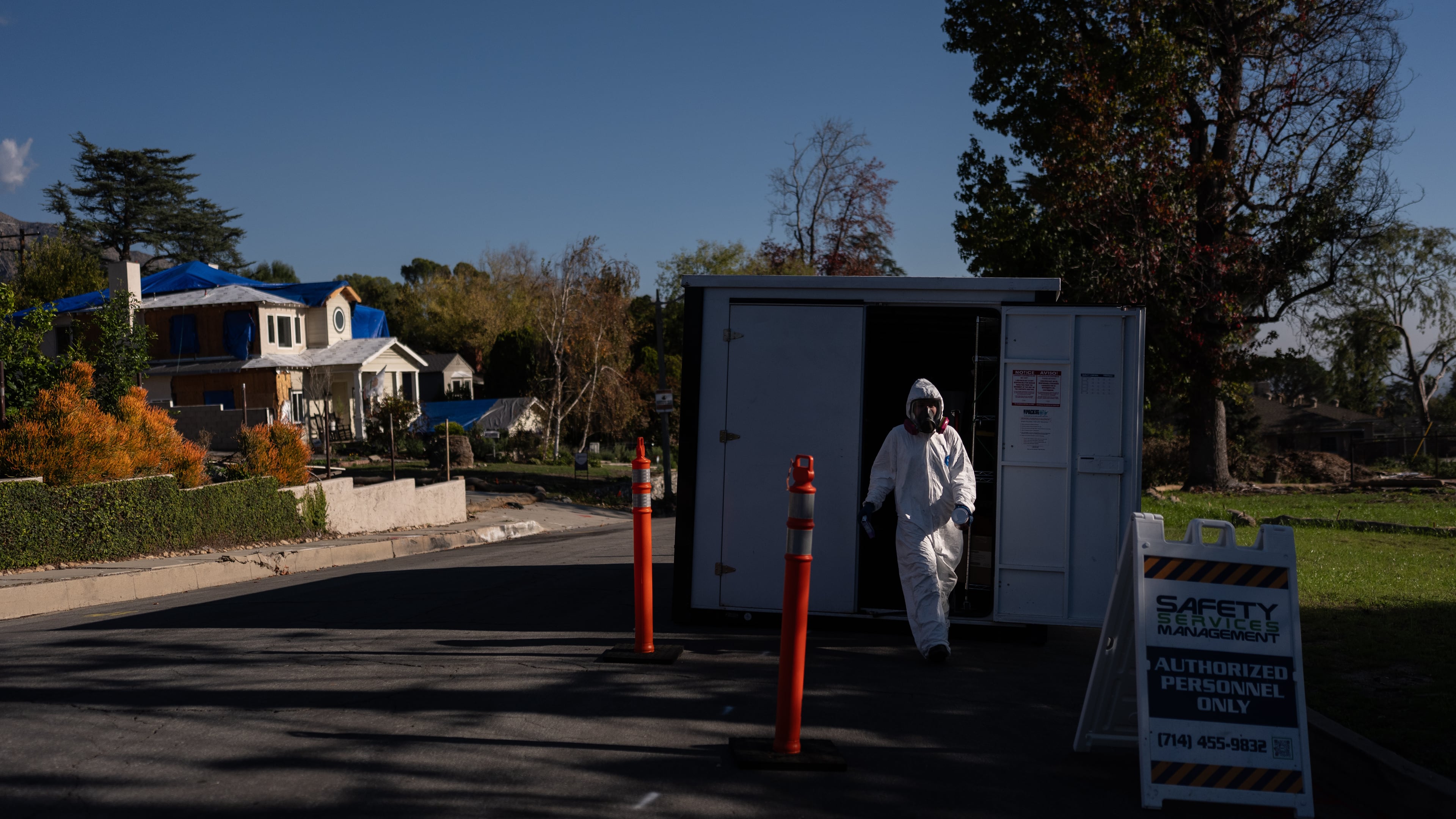 A worker in protective gear exits a storage container at a cleanup site, Dec. 3, 2025, months after the Eaton Fire, in Altadena, Calif. (AP Photo/Jae C. Hong)