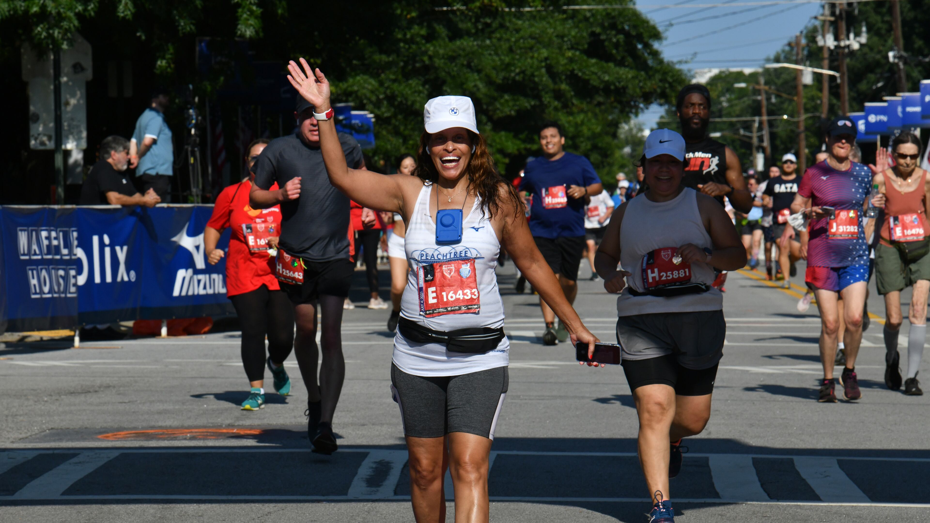 July 4, 2021 Atlanta - Runners react as they cross the finish line during the second day of 2021 Atlanta Journal-Constitution Peachtree Road Race on Sunday, July 4, 2021. (Hyosub Shin / Hyosub.Shin@ajc.com)