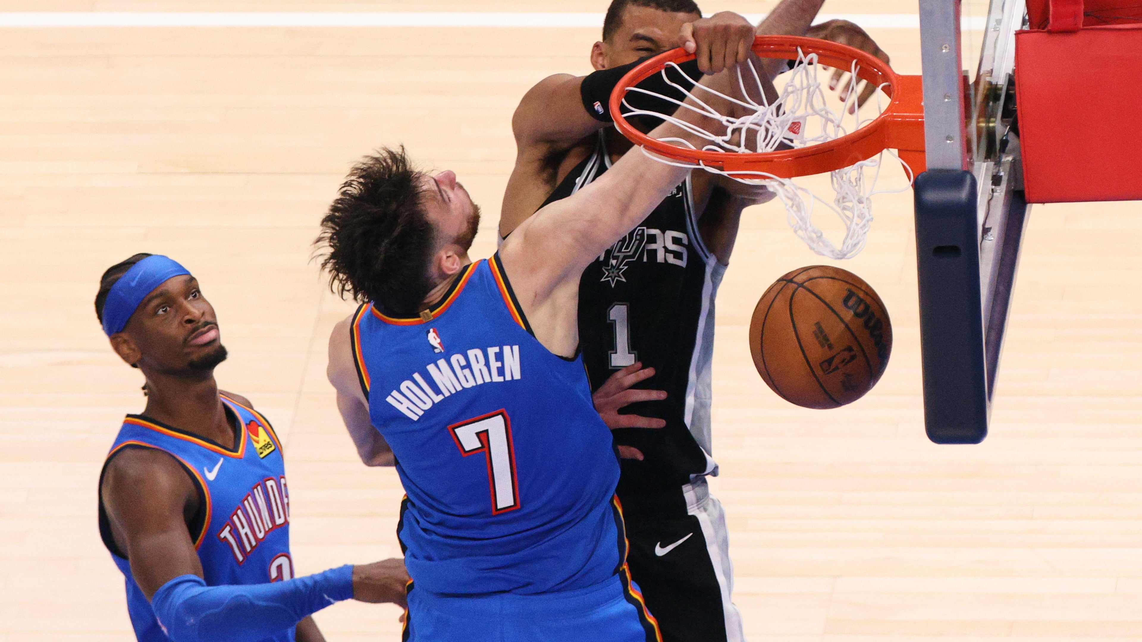 San Antonio Spurs forward Victor Wembanyama (1) dunks while being fouled by Oklahoma City Thunder center Chet Holmgren (7) during the second overtime of Game 1 in a third-round NBA basketball playoffs series Monday, May 18, 2026, in Oklahoma City. (AP Photo/Nate Billings)