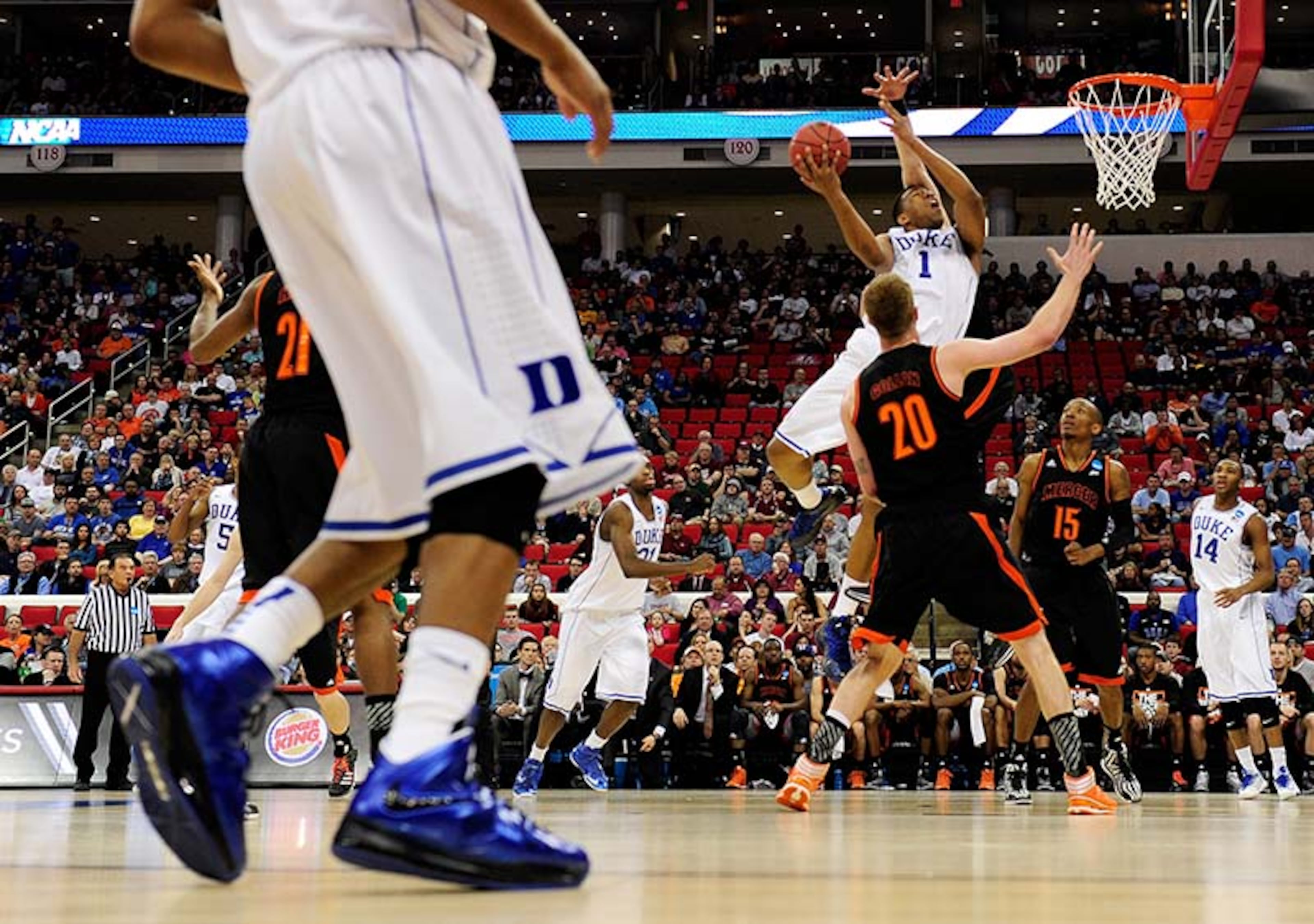 Jabari Parker #1 of the Duke Blue Devils goes up for a shot against Jakob Gollon #20 of the Mercer Bears in the first half in the second round of the 2014 NCAA Men's Basketball Tournament at PNC Arena on March 21, 2014 in Raleigh, North Carolina.