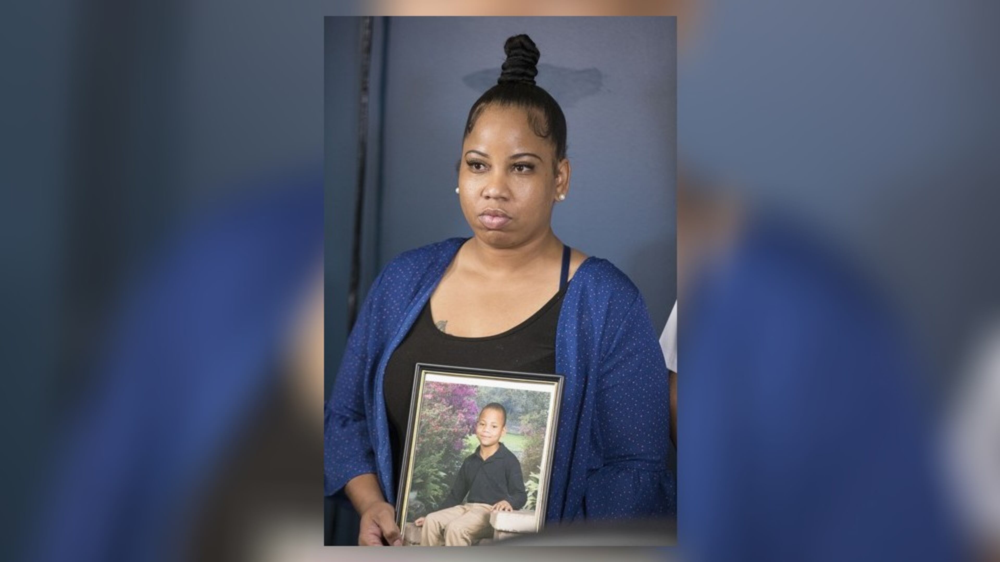 Allison Woods holds a photo of her son Isaiah Payton. The 12-year-old was shot after a football game in August and remains hospitalized. Doctors say he likely won't walk again.