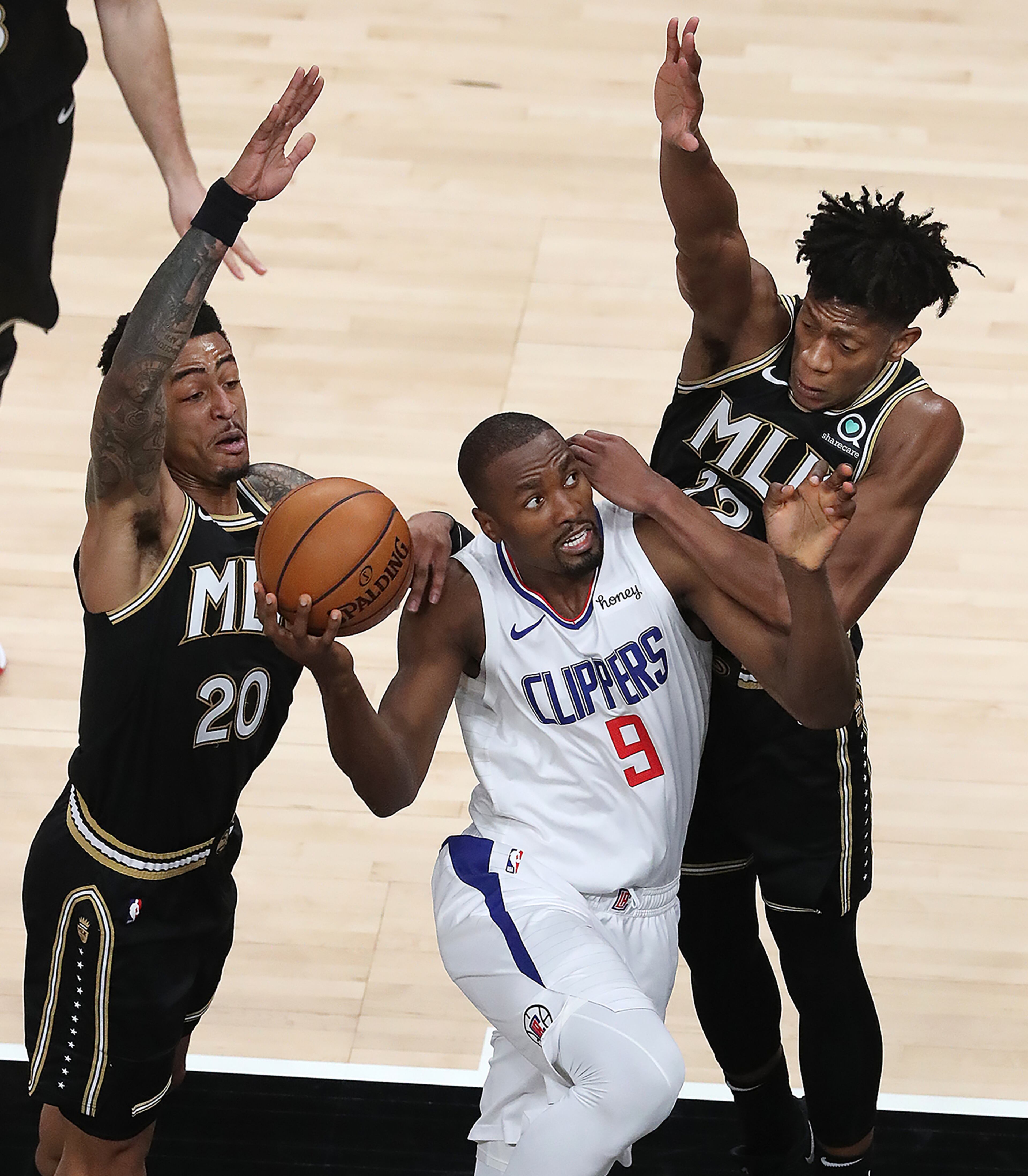 Los Angeles Clippers' Serge Ibaka is double teamed by Atlanta Hawks defenders John Collins (left) and De’Andre Hunter as he goes to the basket in an NBA basketball game on Tuesday, Jan. 26, 2021, in Atlanta. Curtis Compton / Curtis.Compton@ajc.com”