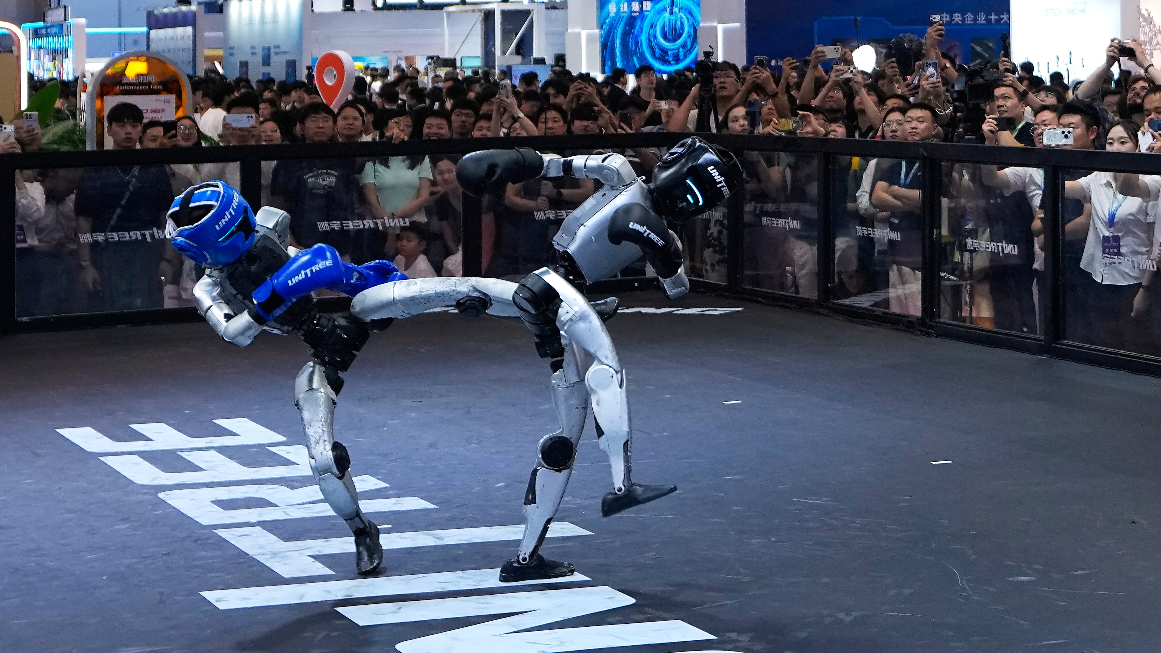 Visitors watch robots demonstrate boxing moves at a booth of Unitree, one of China's largest humanoid robot makers, during the World Robot Conference at the Beijing Yichuang International Convention and Exhibition Centre in Beijing, Wednesday, Aug. 19, 2026. (AP Photo/Andy Wong)