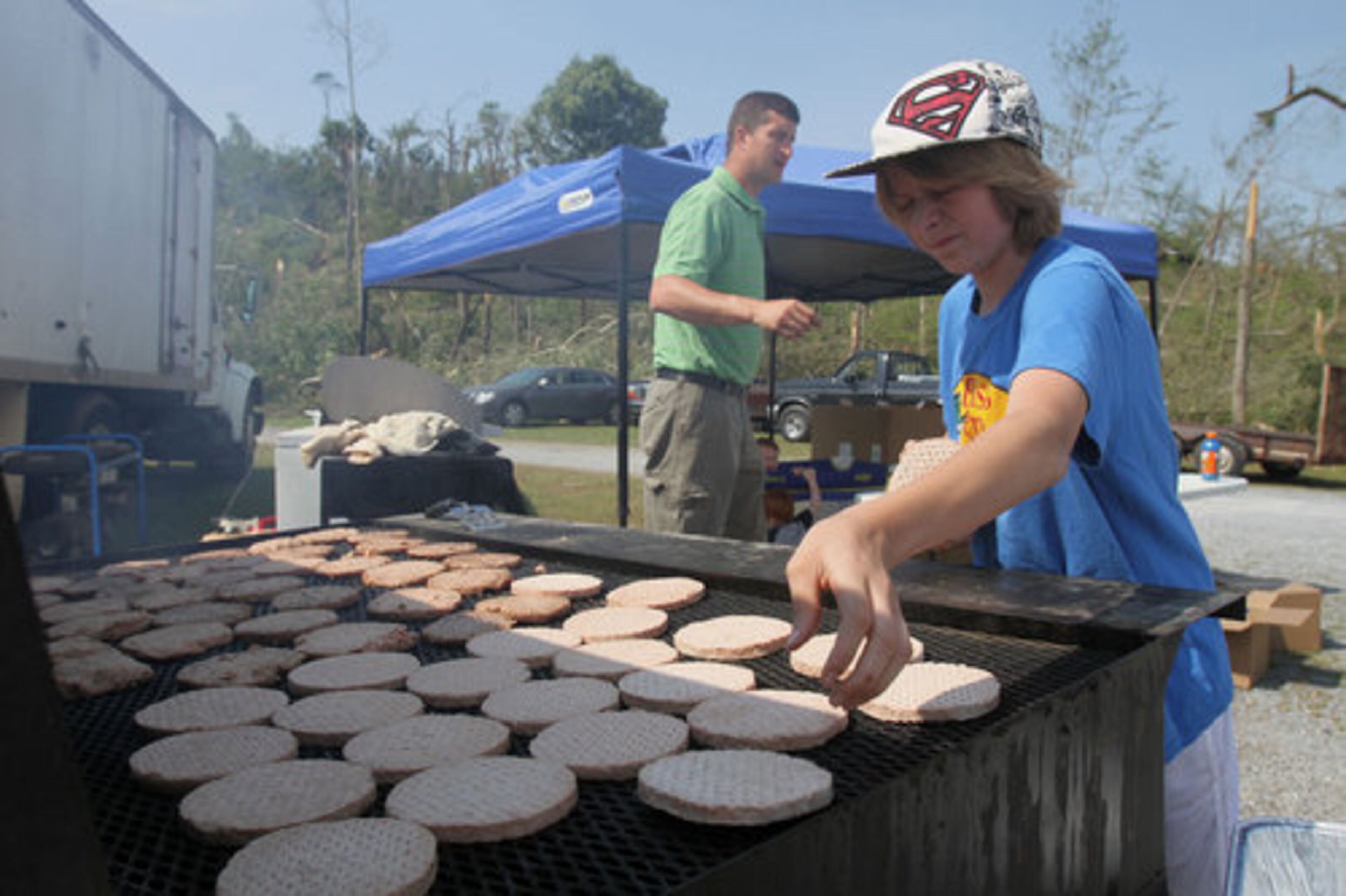 Nathan Harris, 12, and Wesley Morris of 2nd Genesis Ministries help in preparing lunch for members of the Crowe Springs Baptist Church which held their service at their parking lot Sunday in Cartersville, May 1, 2011.