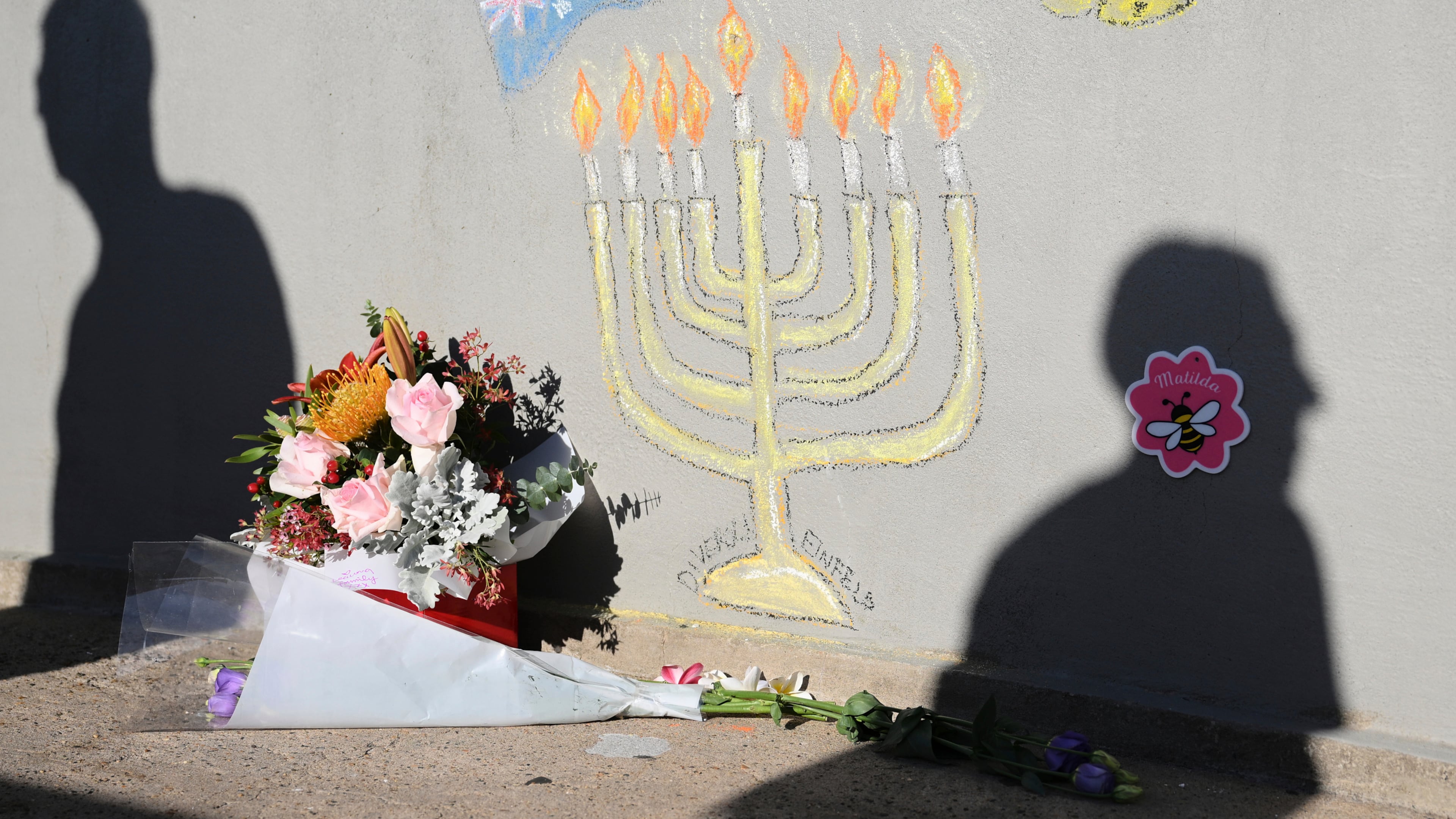 FILE - People walk past a memorial drawn on the wall of a walk bridge as a tribute following Sunday's shooting at Bondi Beach, in Sydney, Friday, Dec. 19, 2025. (AP Photo/Steve Markham, file)