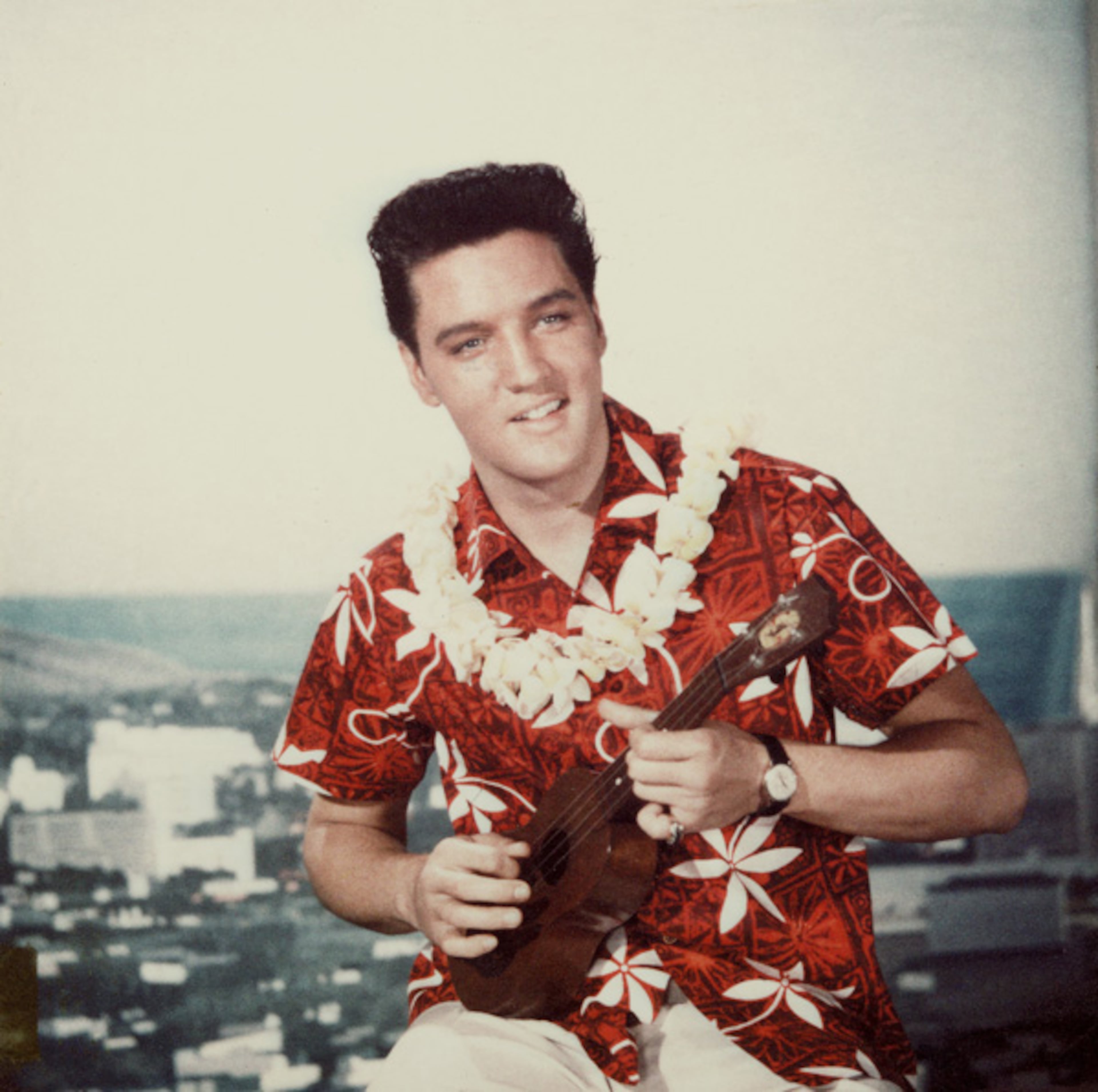 American rock n' roll singer Elvis Presley plays a ukelele, wearing a Hawaiian shirt and lei, in a still from the film 'Blue Hawaii,' directed by Norman Taurog, 1961. (Photo by Paramount Pictures/Courtesy of Getty Images)
