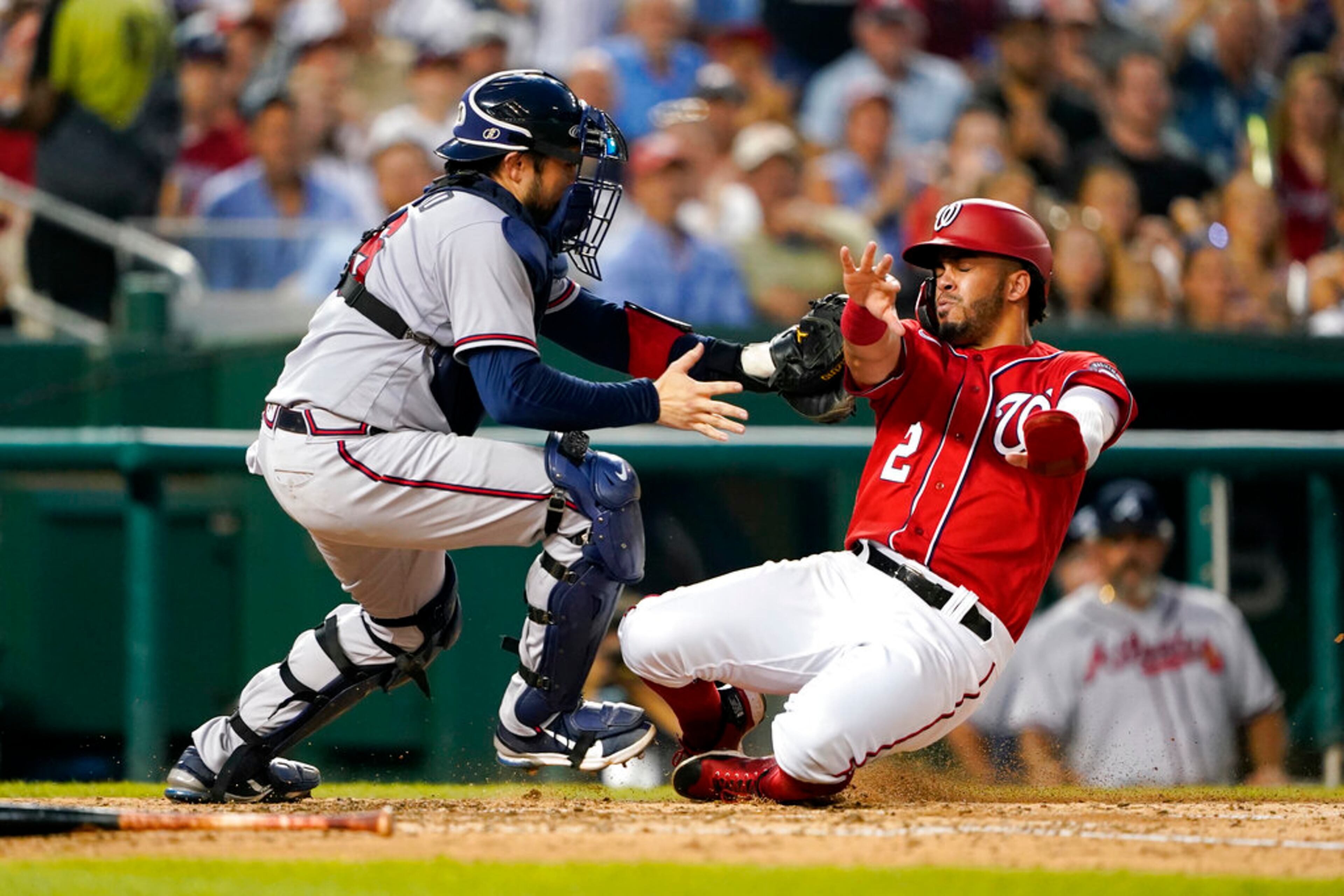Atlanta Braves catcher Travis d'Arnaud, left, tags out Washington Nationals' Luis Garcia at home plate as Garcia attempts to score on Juan Soto's single in the fifth inning of a baseball game, Thursday, July 14, 2022, in Washington. (AP Photo/Patrick Semansky)
